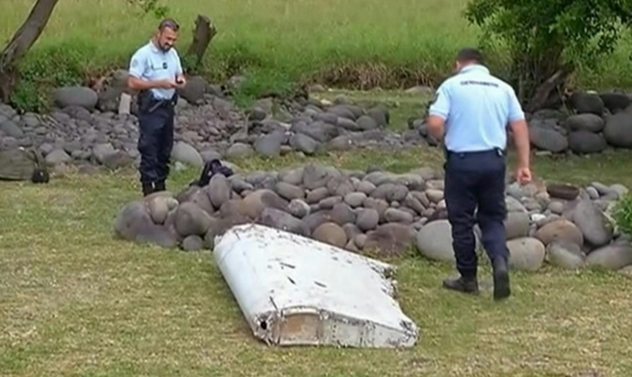In this image taken from video, police officers look over a piece of debris from a plane, Wednesday, July 29, 2015, in Saint-Andre, Reunion.