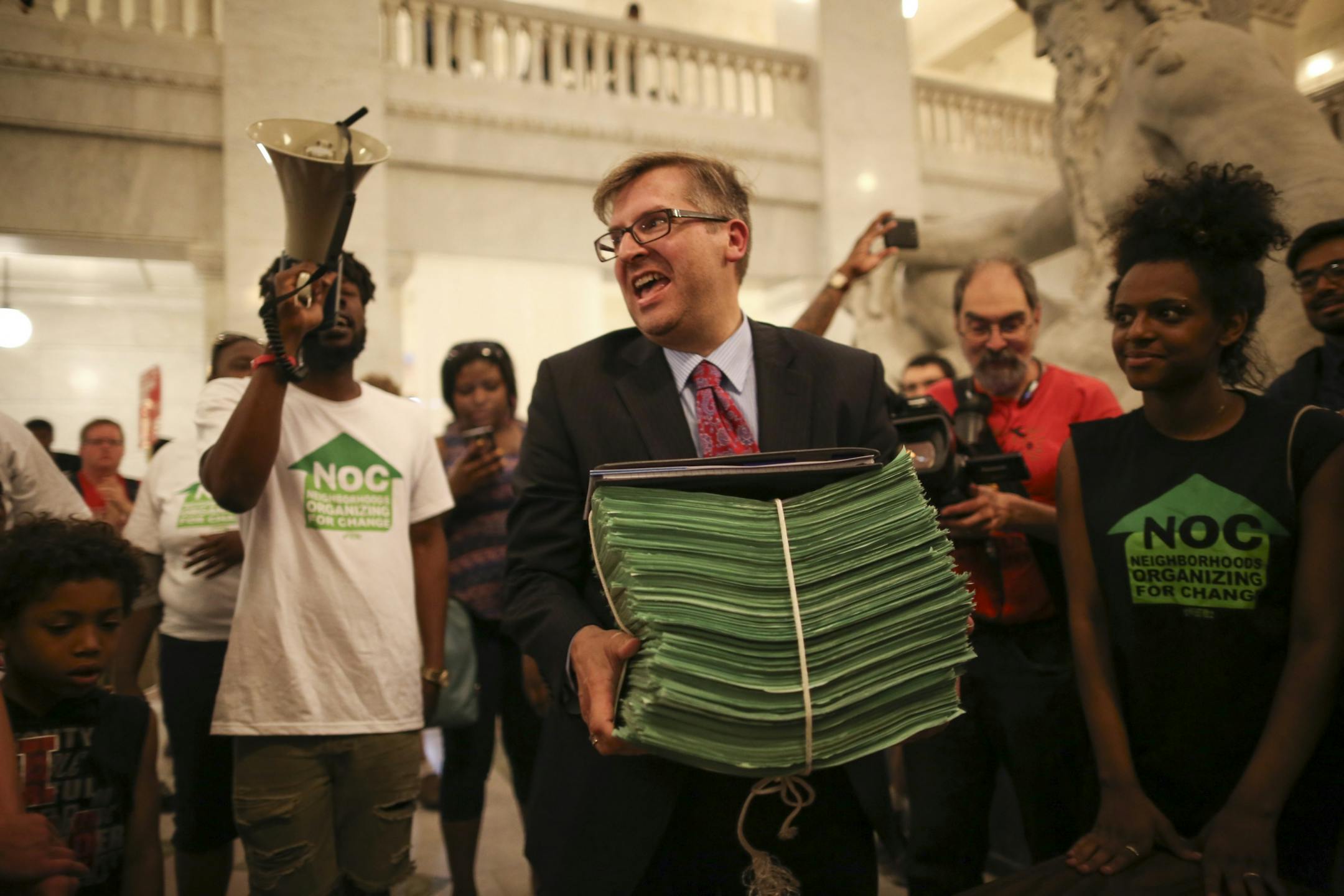 City Clerk Casey Carl carried away the stack of petitions with 20,000 signatures in support of a $15 minimum wage after demonstrators rallied in City Hall and heard speeches before handing over a petition with 20,000 signatures on it to the City Clerk.