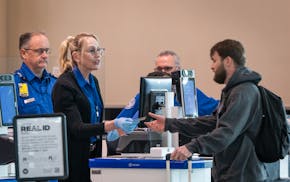 TSA agents check the ID of a passenger at a TSA security checkpoint inside Terminal 2 at Minneapolis - St. Paul International Airport in St. Paul, Min