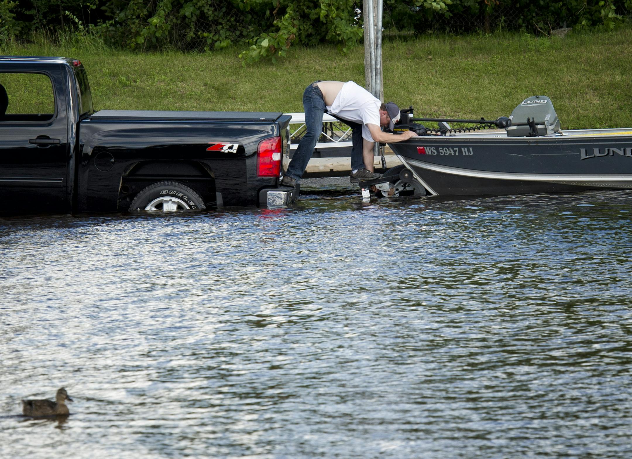 Jeremy Schulz of New Richmond, WI managed to stay dry while putting his fishing boat back on his trailer on the flooded ramp at Jacques Landing Park in Prescott, Wi at the confluence of the St. Croix and Mississippi Rivers Friday afternoon. High water, a swift current and a no wake zone on the Mississippi River at Kings Cove Marina in Hastings, Minnesota made river boating difficult Friday, June 28, 2013. ] GLEN STUBBE * gstubbe@startribune.com
