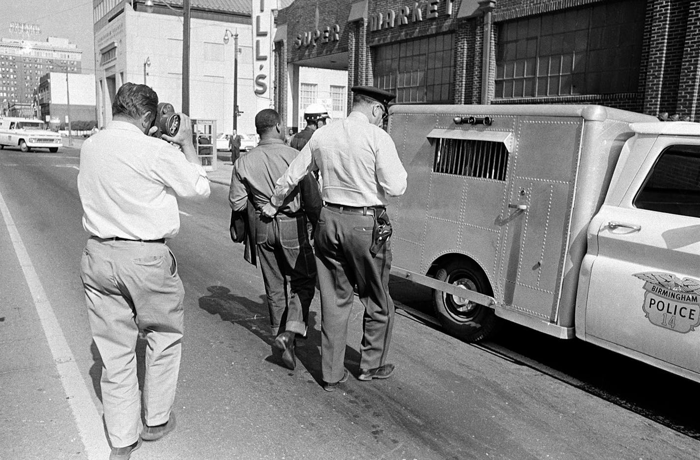 A police officer holds the Rev. Martin Luther King Jr. by his belt as he leads him to the paddy wagon, following arrest at an anti-segregation protest in downtown Birmingham, Ala., on April 13, 1963. An unidentified cameraman is documenting the scene. (AP Photo) ORG XMIT: APHS124