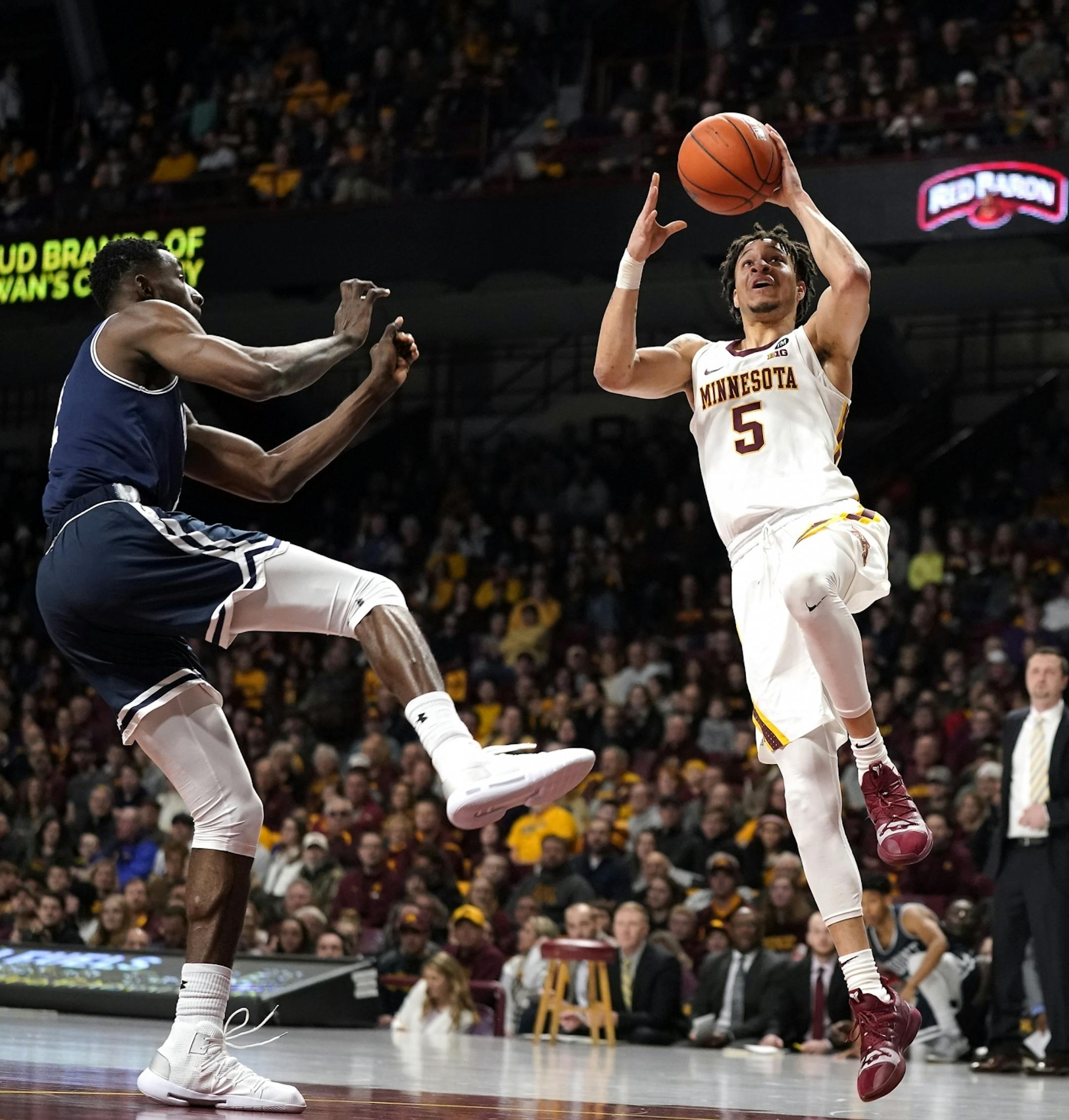 Minnesota guard Amir Coffey (5) shoots during the first half.