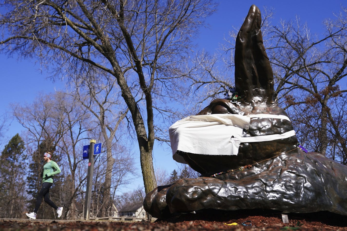 A jogger passed the Minnehaha bunny, after someone playfully added a protective mask during the coronavirus pandemic, Friday, March 20, in south Minneapolis.