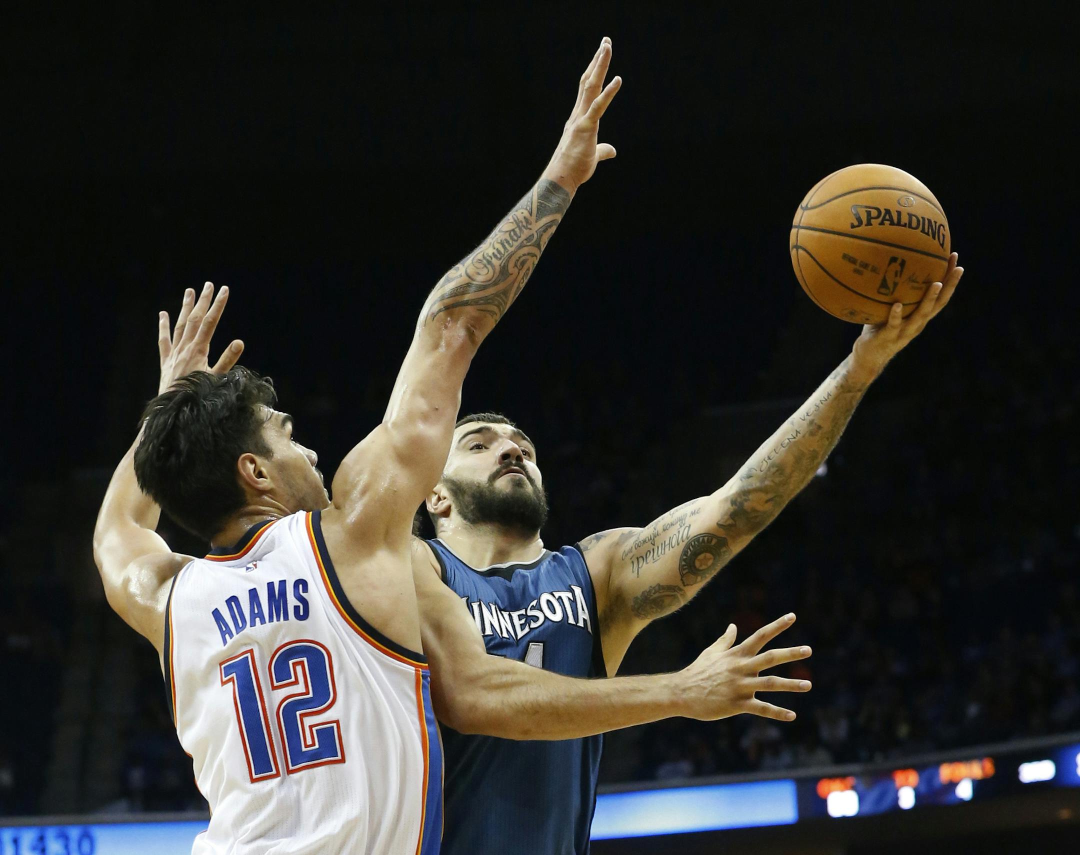Minnesota Timberwolves center Nikola Pekovic, right, shoots in front of Oklahoma City Thunder center Steven Adams (12) in the third quarter of an NBA preseason basketball game in Tulsa, Okla., Sunday, Oct. 19, 2014. Minnesota won 112-94. (AP Photo/Sue Ogrocki) ORG XMIT: MIN2014101922181450