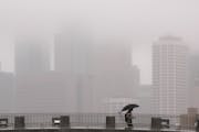 The drizzle obscured the Minneapolis skyline as a pedestrian walked across one of the foot bridges over Washington Ave. on the University of Minnesota