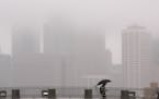 The drizzle obscured the Minneapolis skyline as a pedestrian walked across one of the foot bridges over Washington Ave. on the University of Minnesota