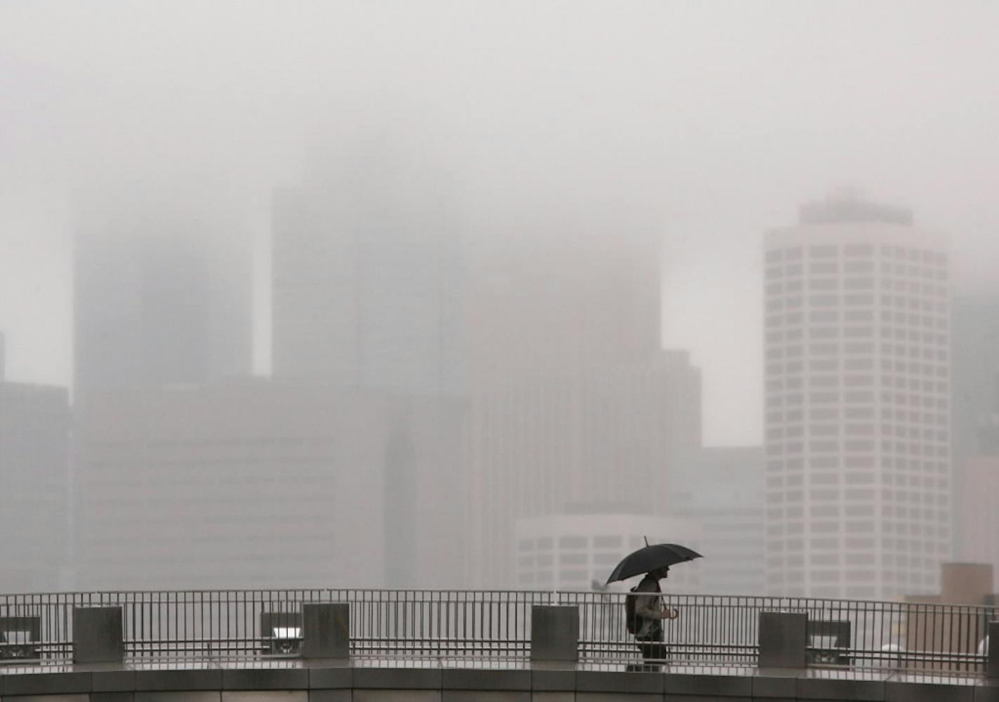 The drizzle obscured the Minneapolis skyline as a pedestrian walked across one of the foot bridges over Washington Ave. on the University of Minnesota campus Friday afternoon.