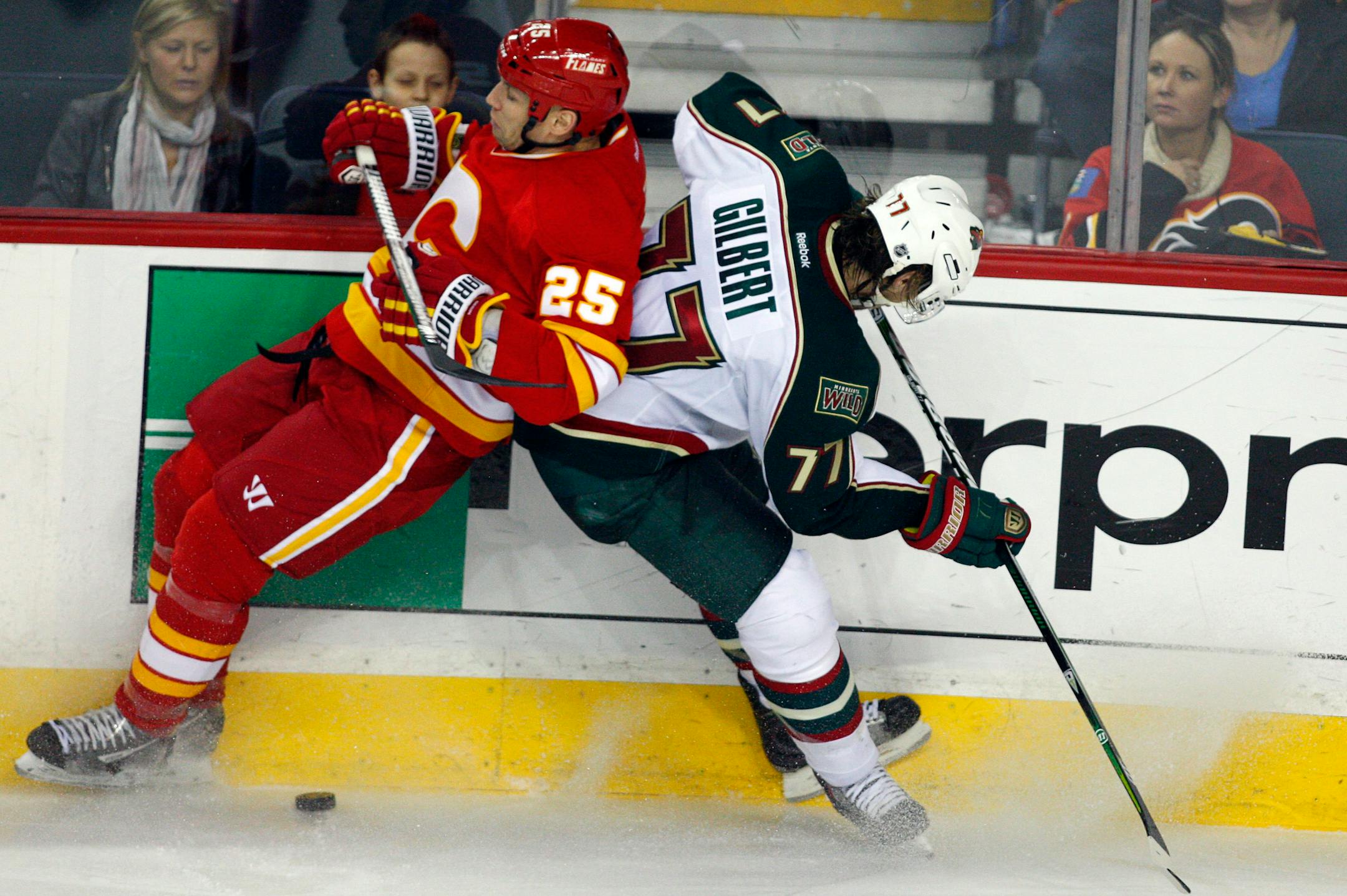 Minnesota Wild's Tom Gilbert, right, collides with Calgary Flames' Steve Begin during the third period of an NHL hockey game in Calgary, Alberta, Saturday, Feb. 23, 2013. (AP Photo/The Canadian Press, Jeff McIntosh)