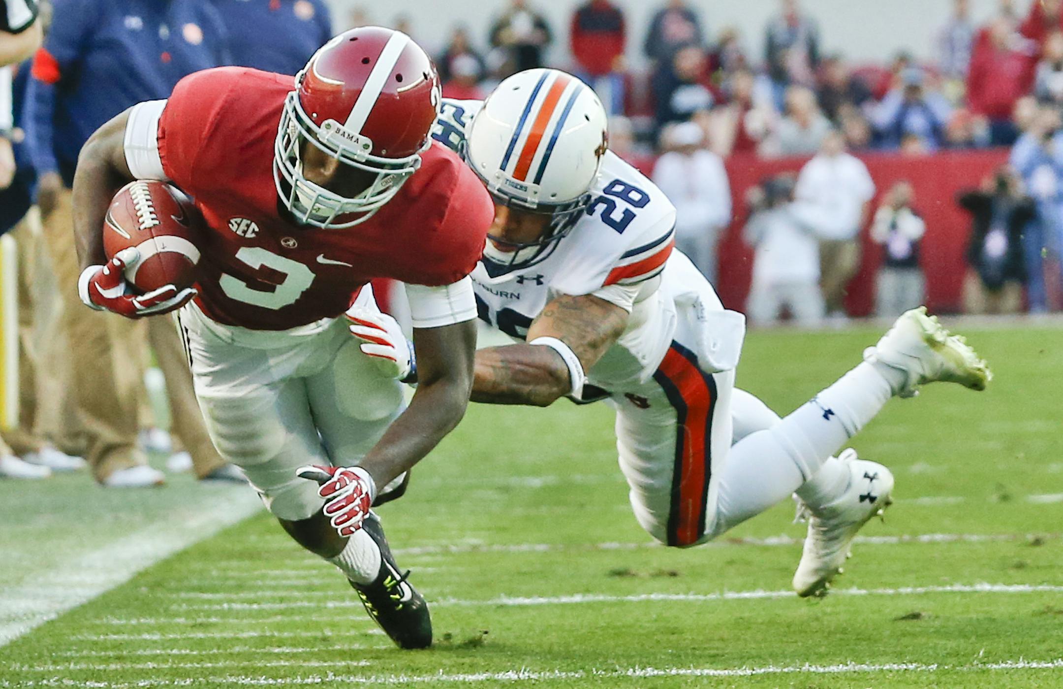 Alabama wide receiver Calvin Ridley dives to gain more yards against Auburn defensive back Tray Matthews during the first half of the Iron Bowl NCAA college football game, Saturday, Nov. 26, 2016, in Tuscaloosa, Ala. (AP Photo/Brynn Anderson)