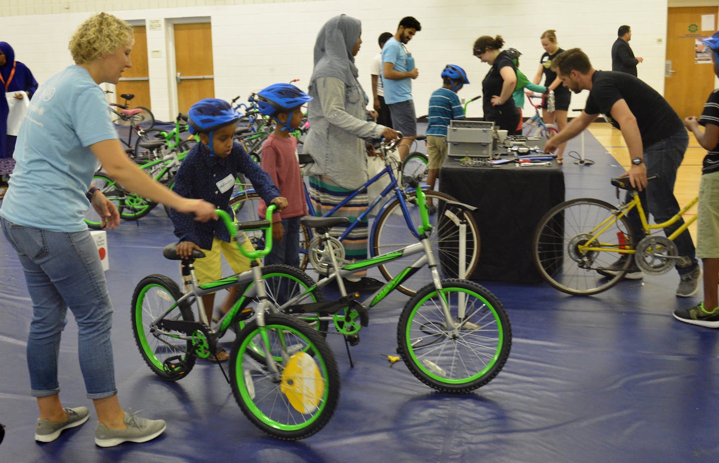 The Director of Community Relations, Allina Health, Alison Pence giving a bicycle to a kid during free bicycle distribution ceremony at Brian Coyle Community Center. Photo Credit: Salman Yousafzai?/Star Tribune