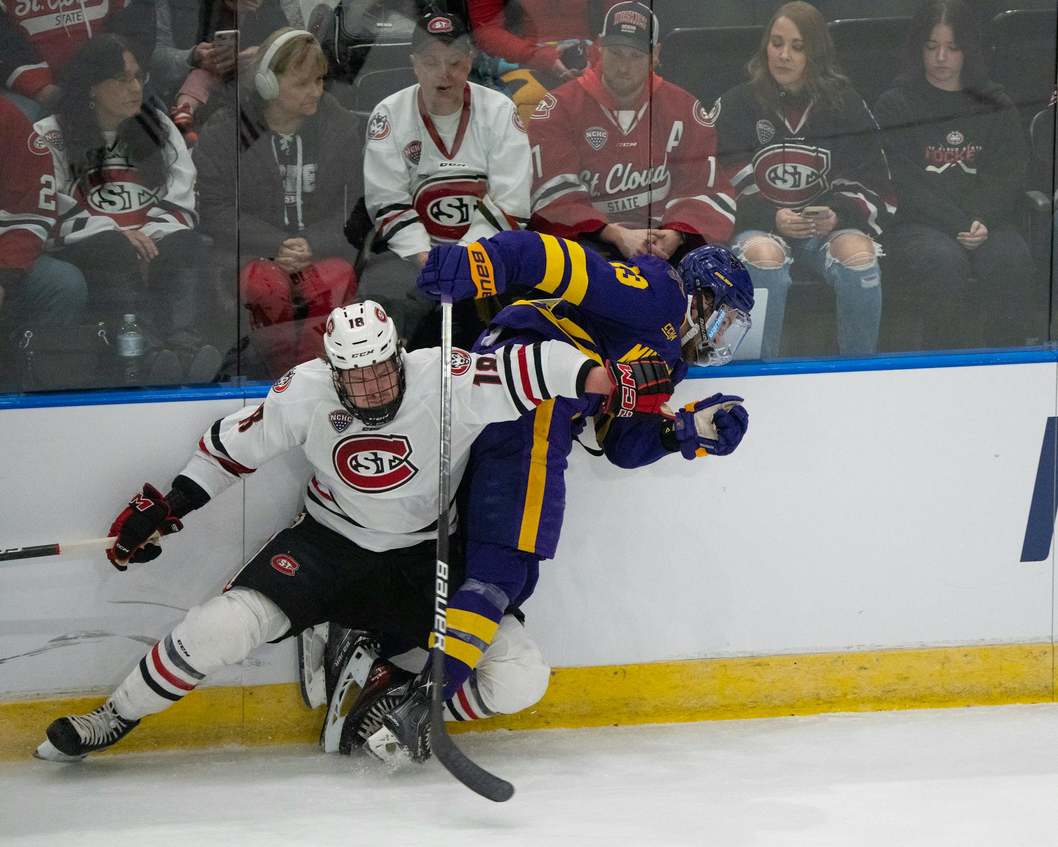 St. Cloud State Huskies defenseman Brendan Bushy (18) checked Minnesota State Mavericks forward Brendan Furry (13) into the boards in the first period.