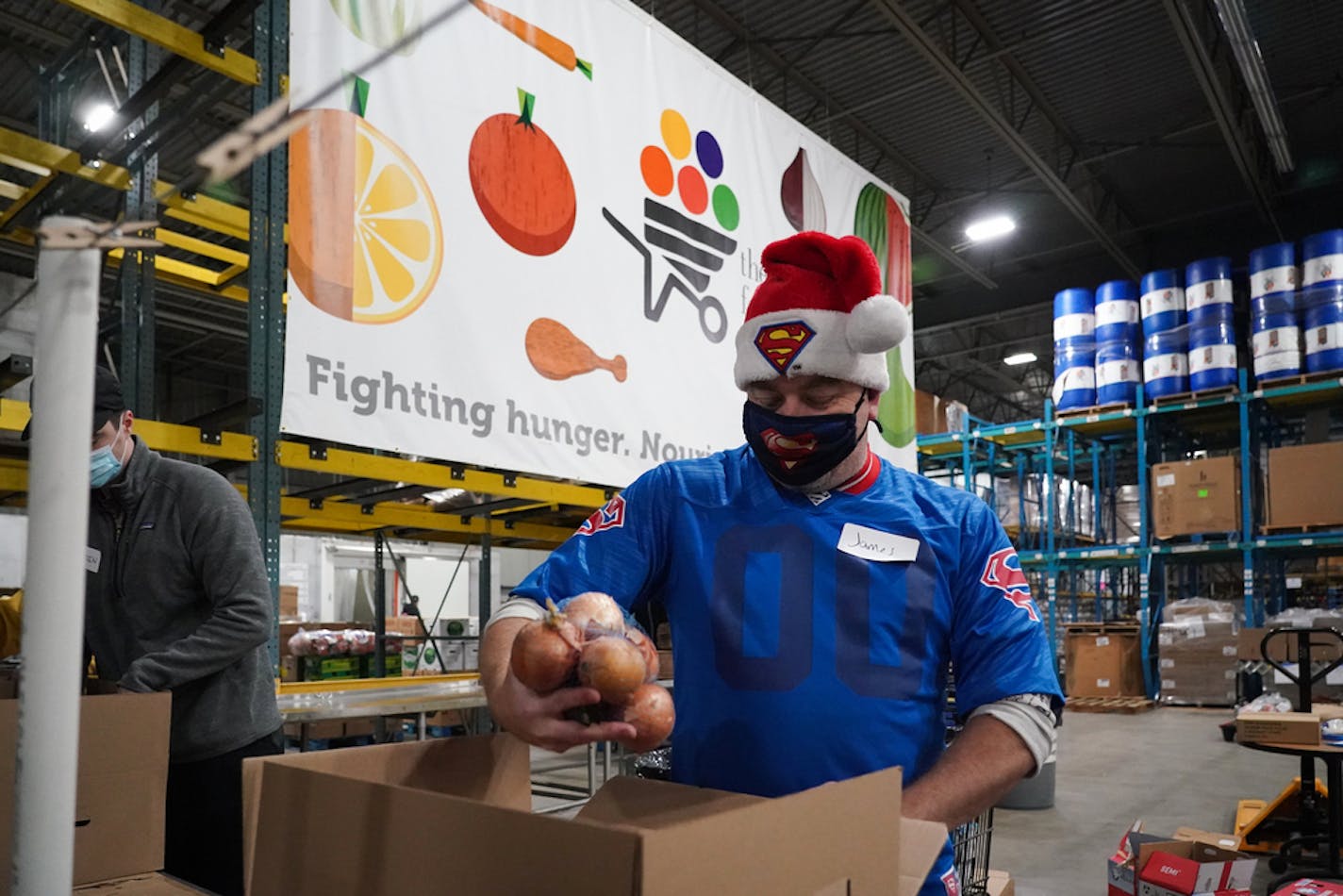 More than a dozen volunteers packed and sorted food at the Food Group in New Hope on Friday, Dec. 18, 2020. In this photo, James Gottfried, a frequent volunteer, filled a box with food. Gottfried, who has been volunteering at the Food Group since the start of the pandemic, said he's become 'addicted' to volunteering and would consider a career change to work with non-profits because of the good they do for people.