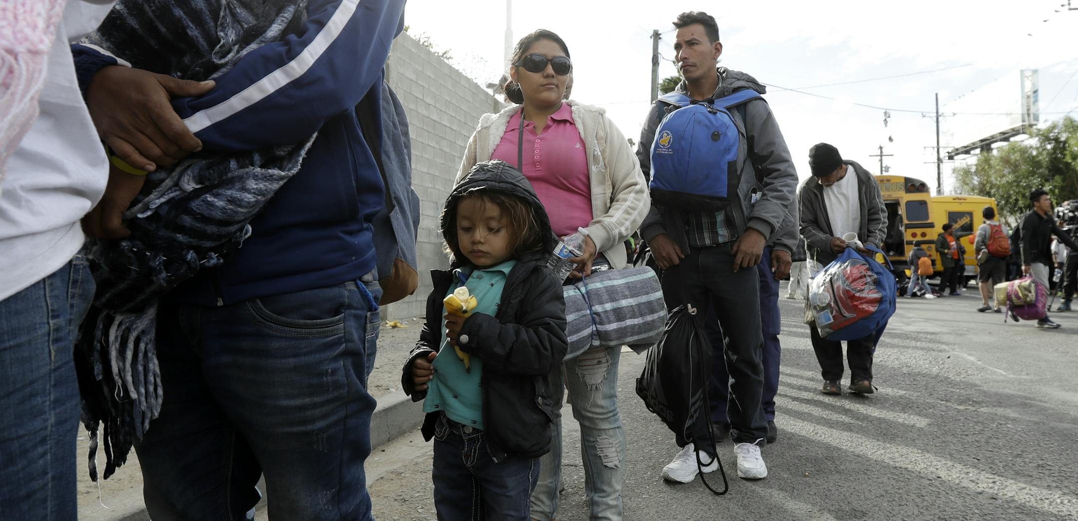 Central American migrants wait in line for a meal at a shelter Wednesday, Nov. 14, 2018, in Tijuana, Mexico. Migrants in a caravan of Central Americans scrambled to reach the U.S. border, catching rides on buses and trucks for hundreds of miles in the last leg of their journey Wednesday as the first sizable groups began arriving in the border city of Tijuana. (AP Photo/Gregory Bull)