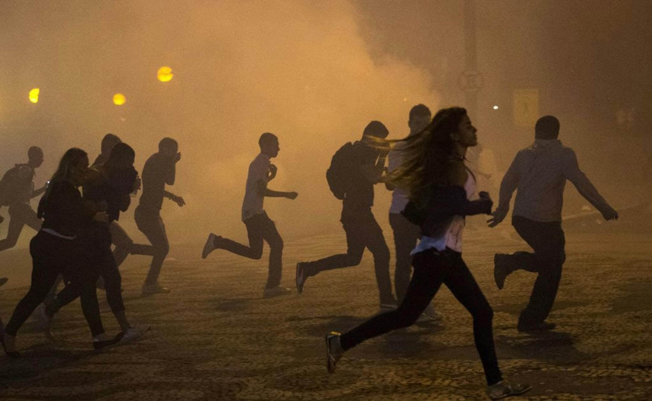 Protesters run from the clouds of tear gas during an anti-government protest in Rio de Janeiro, Brazil, Thursday, June 20, 2013.