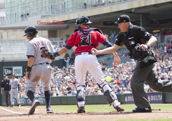 Home plate umpire Mike Everitt, right, calls out Detroit Tigers runner Ian Kinsler, left, at home after a tag by Minnesota Twins catcher Jason Castro,