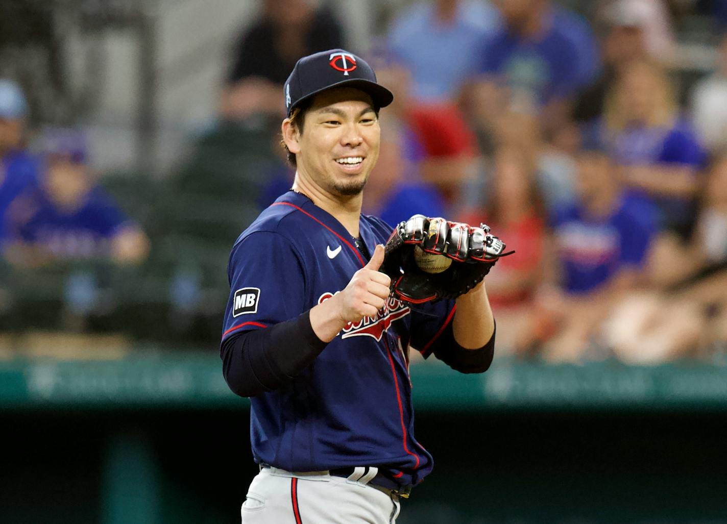 Minnesota Twins starting pitcher Kenta Maeda (18) gives a thumbs up toward the manager and trainer as they approach the mound during the game against the Texas Rangers at a baseball game Sunday, June 20, 2021, in Arlington, Texas. (AP Photo/Richard W. Rodriguez)