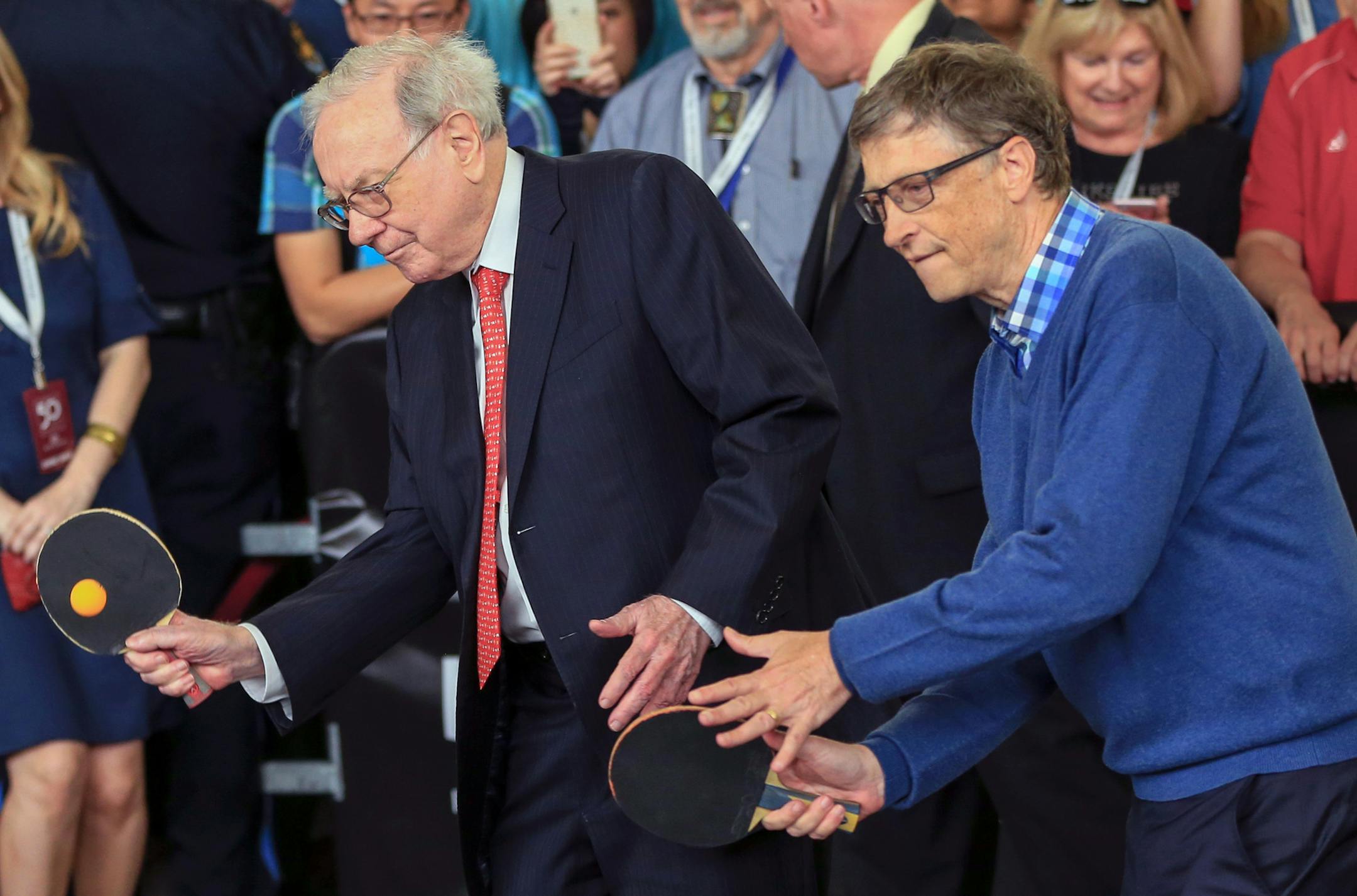 Berkshire Hathaway Chairman and CEO Warren Buffett, left, and Microsoft co-founder Bill Gates play table tennis against prodigy Ariel Hsing, unseen, outside the Borsheims jewelry store, a Berkshire Hathaway subsidiary, in Omaha, Neb., Sunday, May 3, 2015. The annual Berkshire shareholders weekend is coming to a close one day after more than 40,000 people attended a question and answer session with Warren Buffett and his Vice Chairman Charlie Munger. (AP Photo/Nati Harnik)