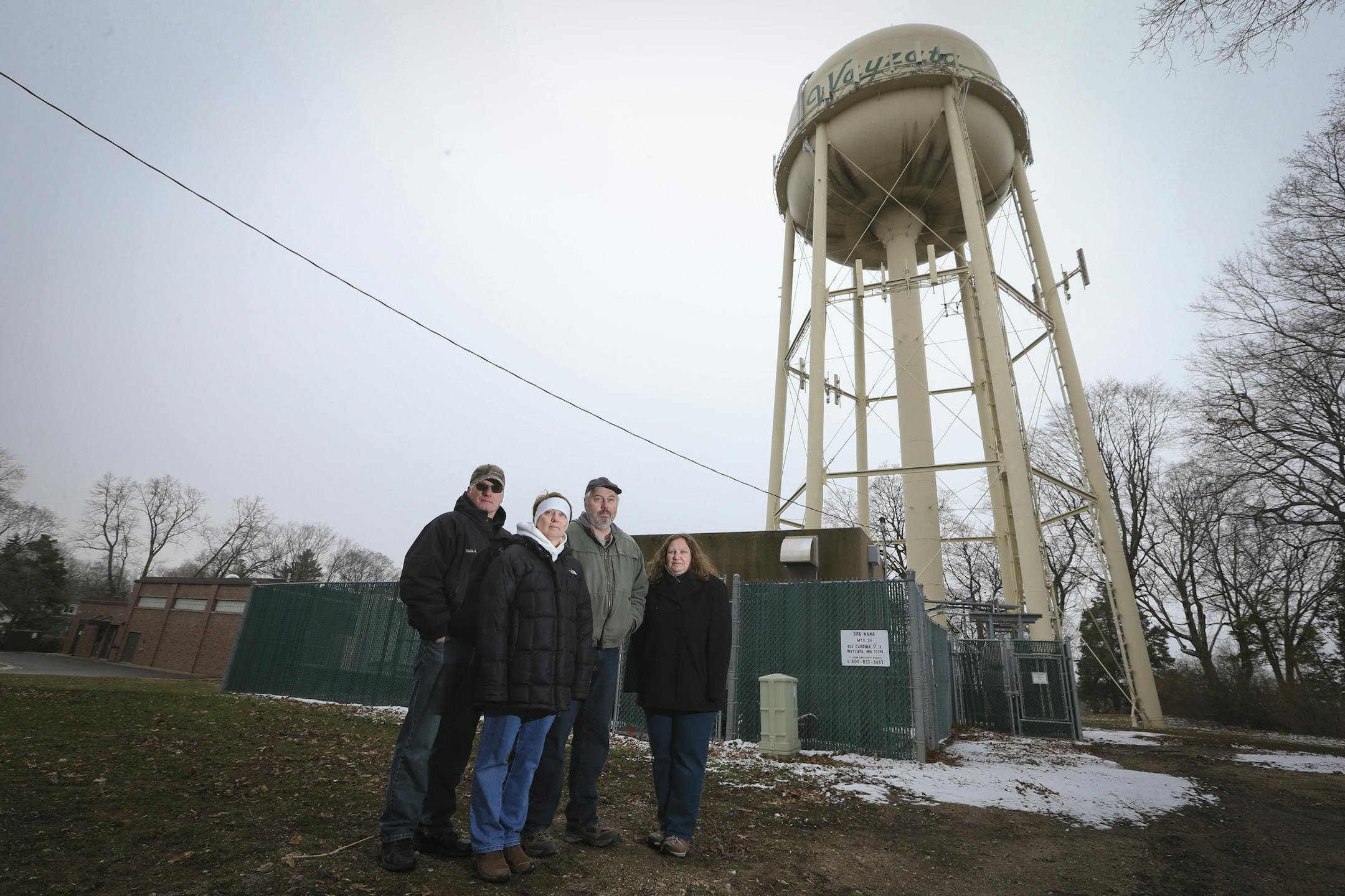 From the left; Neighbors Mark and Susan Hughes and Dale and Cathy Carlson stood in front of a cluster of fenced-in areas that houses cellphone antenna equipment in Wayzata, Minn., on Wednesday, April 16, 2014. The decades-long controversy over cell phone antennas stuck to Wayzata's water tower in a city park is surfacing again with the cell company agreeing this week to spend $10,000 on studying the impact of the cellular installation's impact on the neighboring homes. Residents in the area say