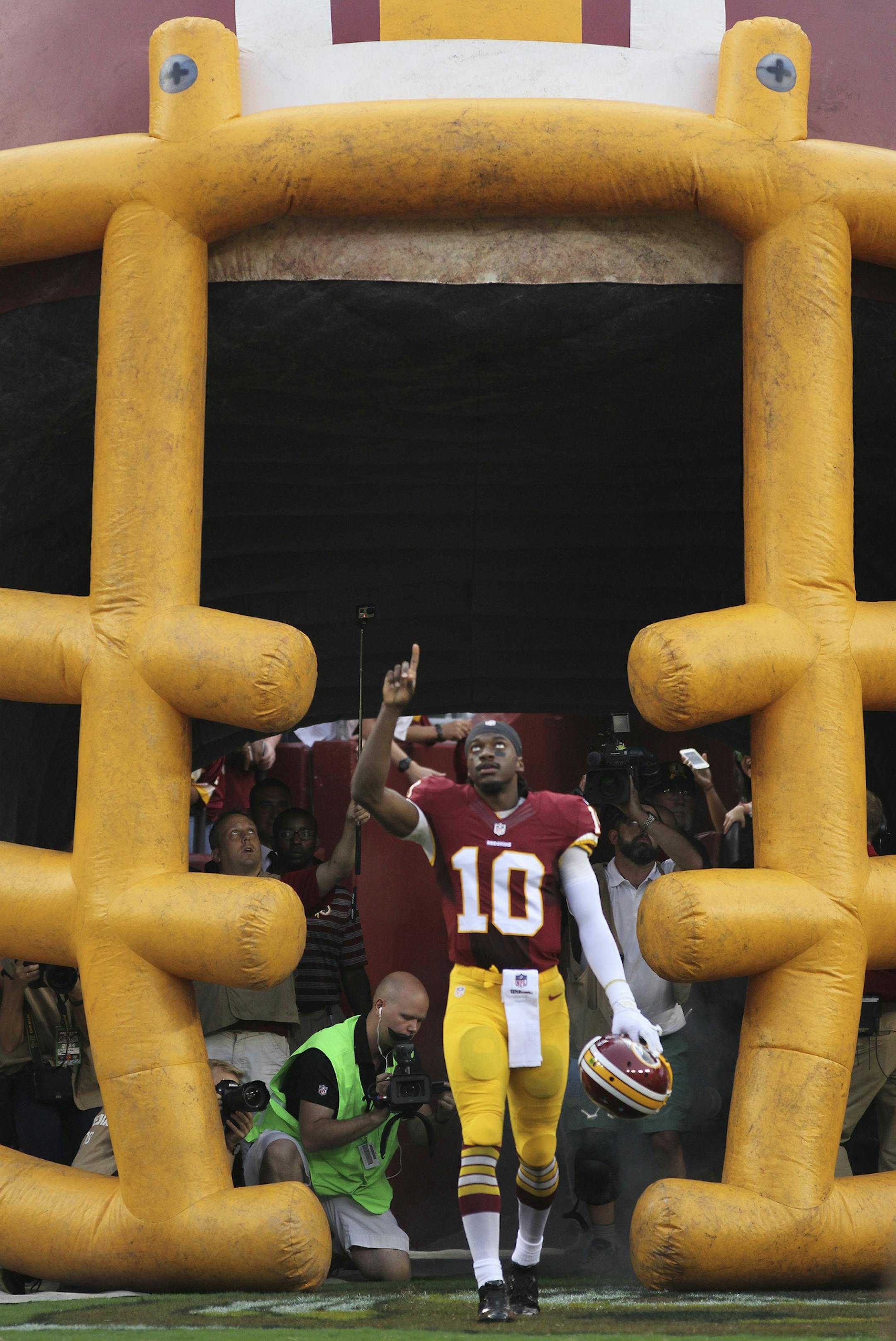 Washington Redskins quarterback Robert Griffin III points skyward during his introduction before the first half of an NFL football preseason game against the New England Patriots in Landover, Md., Thursday, Aug. 7, 2014. (AP Photo/Connor Radnovich)