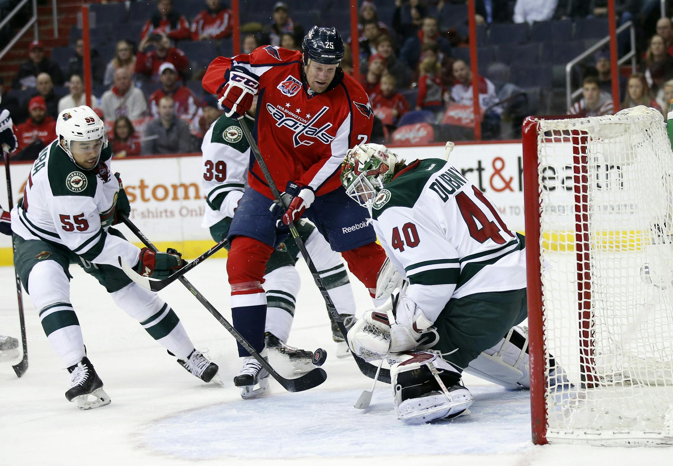 Washington Capitals left wing Jason Chimera (25) works the puck in front of Minnesota Wild goalie Devan Dubnyk (40) with defenseman Matt Dumba (55) nearby, during the first period of an NHL hockey game Thursday, March 5, 2015, in Washington. (AP Photo/Alex Brandon)