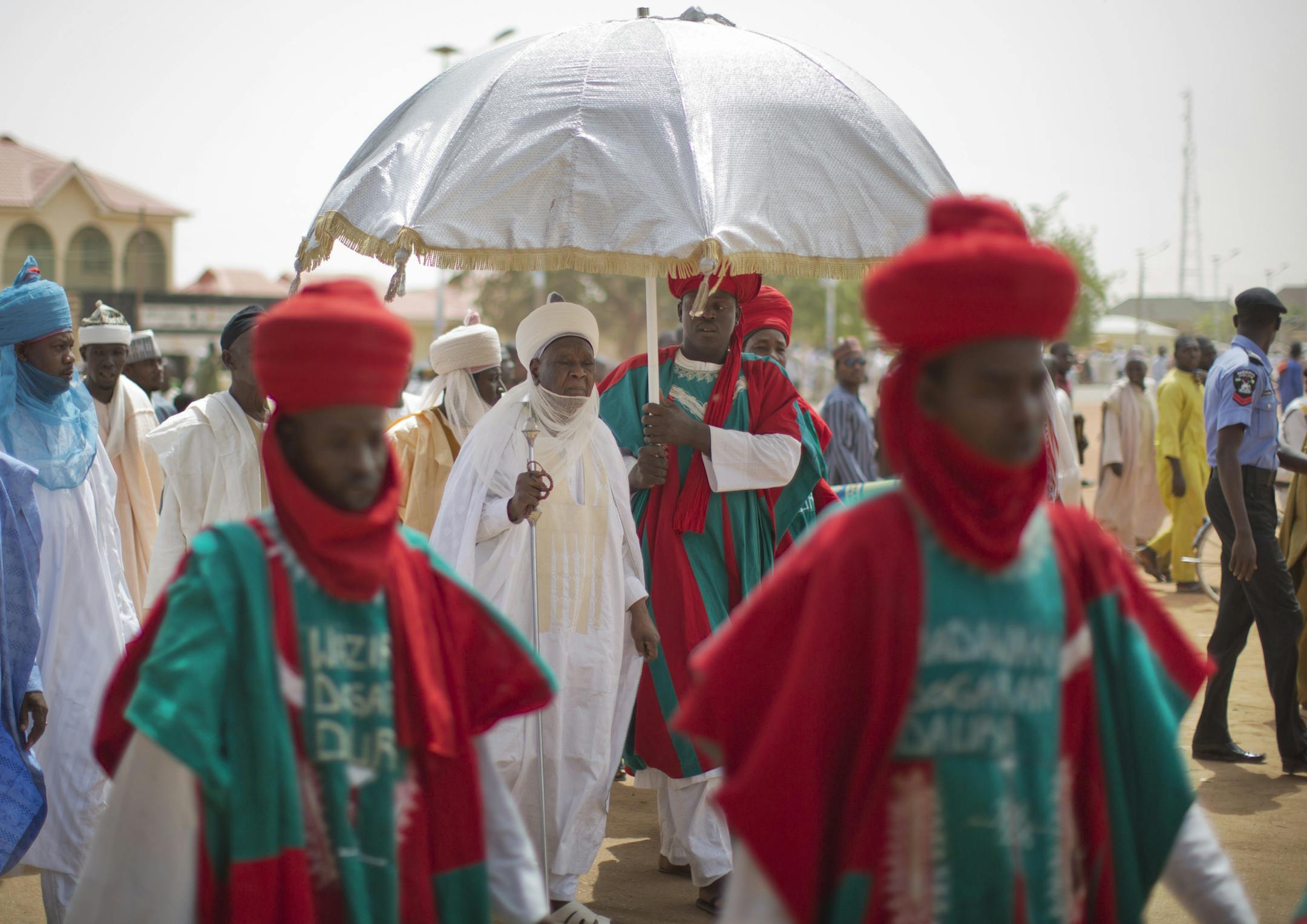 The Emir of Daura Faruk Umar Faruk, center, returns from traditional Friday prayers with hundreds of other worshippers outside the Emir's Palace Mosque in Daura, the home town of opposition candidate Gen. Muhammadu Buhari, in Katsina state in northern Nigeria Friday, March 27, 2015. When Nigerians go to the polls on Saturday, all vehicles except those on official election duty will be banned from the roads during voting day. (AP Photo/Ben Curtis)