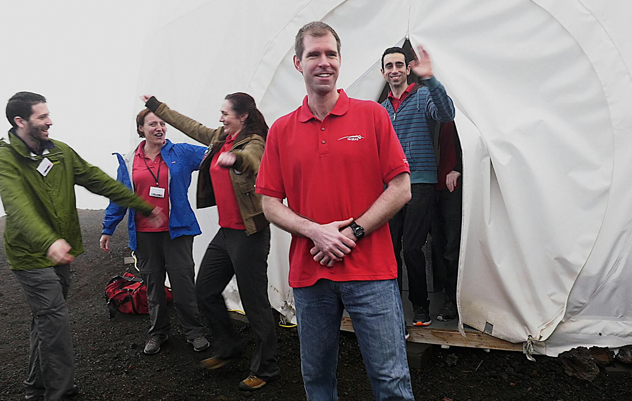 In this photo provided by the University of Hawaii, six scientists celebrate as they exit from their Mars simulation habitat on slopes of Mauna Loa on the Big Island, Hawaii, Sunday, Aug. 28, 2016. The scientists completed a yearlong Mars simulation in Hawaii on Sunday, where they lived in the dome in near isolation. (University of Hawaii via AP)