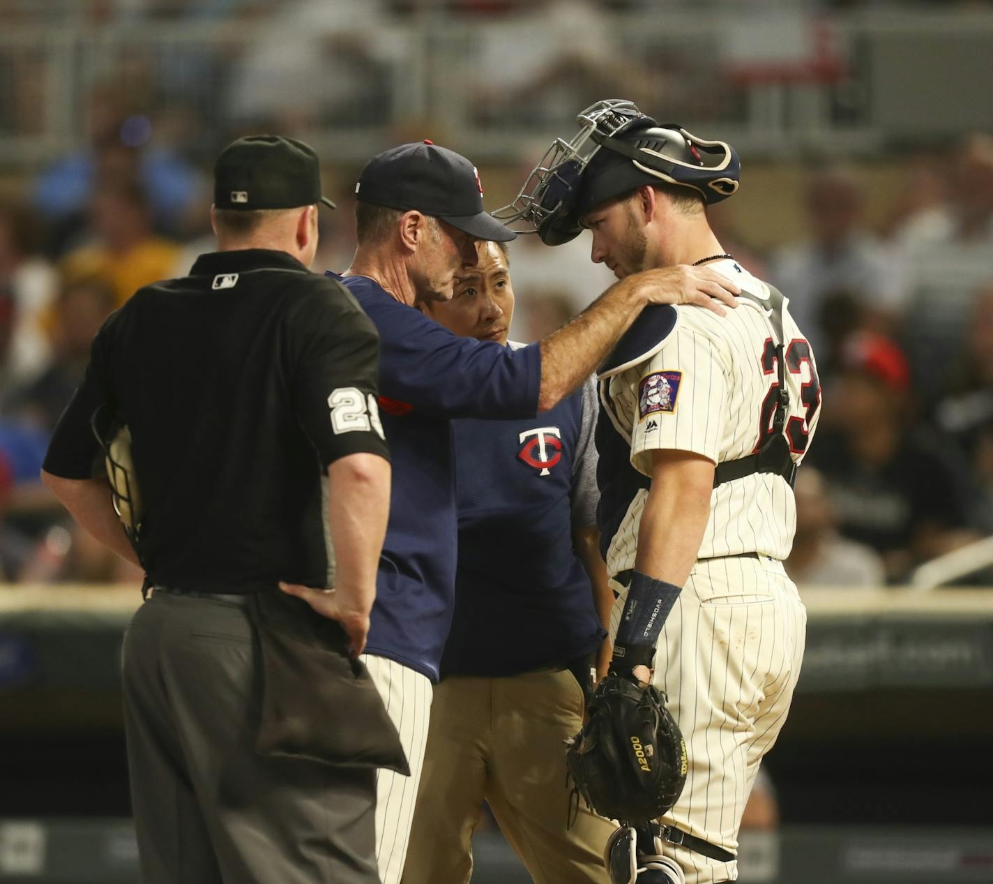 Minnesota Twins catcher Mitch Garver (23) spoke with manager Paul Molitor and a trainer after being hit by a foul ball in the second inning. He left the game after the inning was completed.