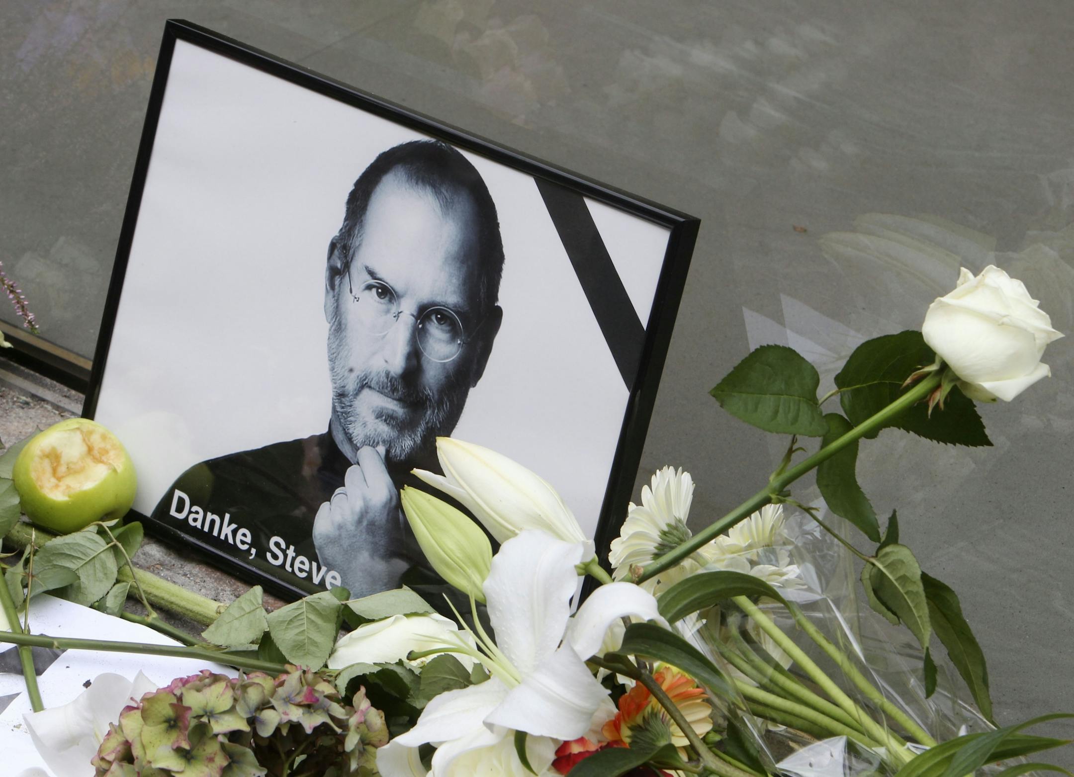 A bouquet of flowers and a picture of Steve Jobs are placed to pay tribute to Steve Jobs, the Apple founder and former CEO, at an Apple Store in Frankfurt, Germany.