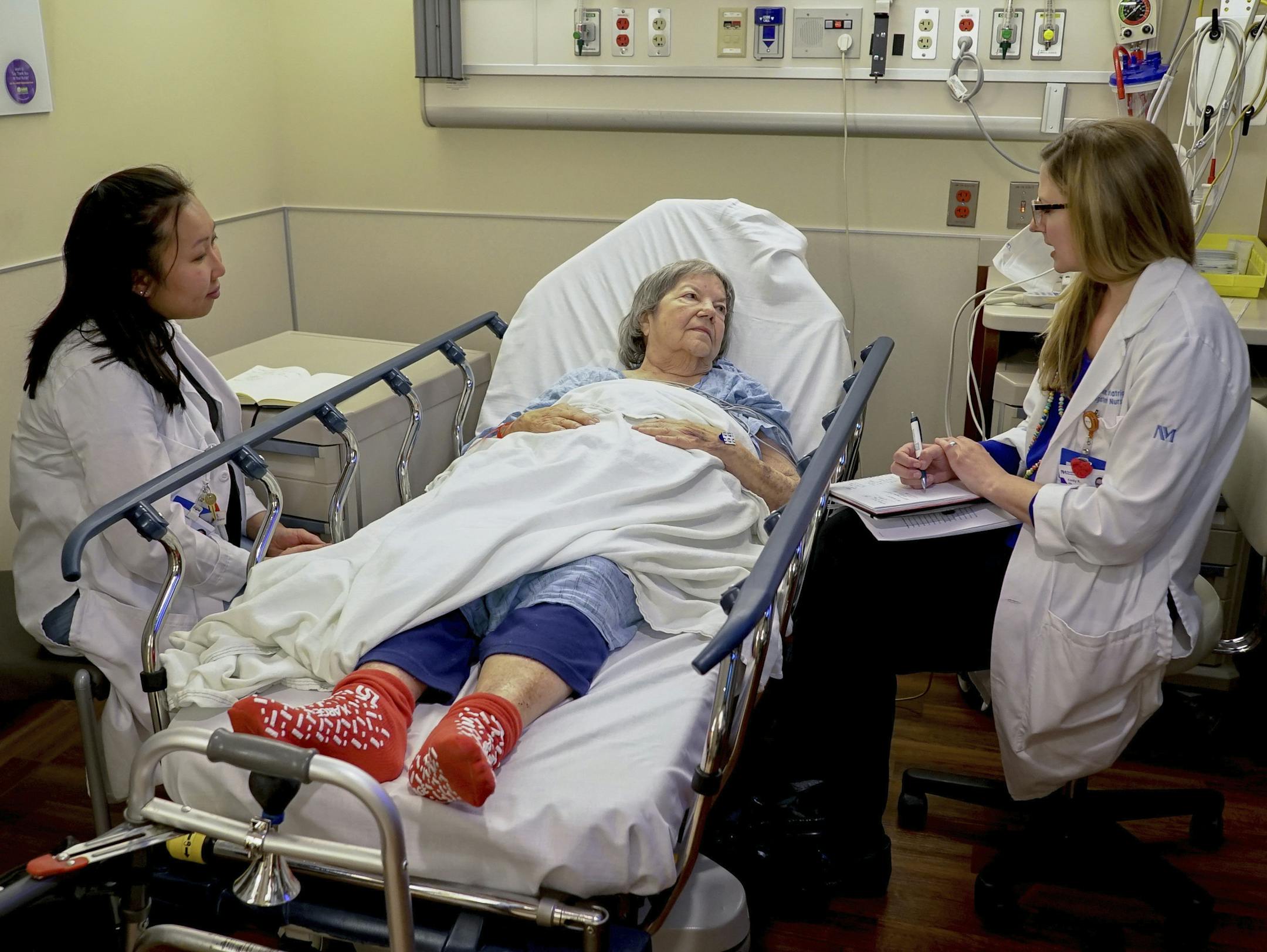 Nurses Lisa Lui-Popelka, left, and&#xa0;Emily Ruben, right, talk with&#xa0;Northwestern Memorial Hospital patient Carol Wittwer at her bedside in a special wing of the Emergency Department in Chicago on Jan. 10, 2018. Popelka and Ruben are specially trained to treat older patients and, when possible, arrange help for them at home. That prevents unneeded hospital admissions and a host of potential problems that can make older patients sicker.&#xa0;(AP Photo/Teresa Crawford)