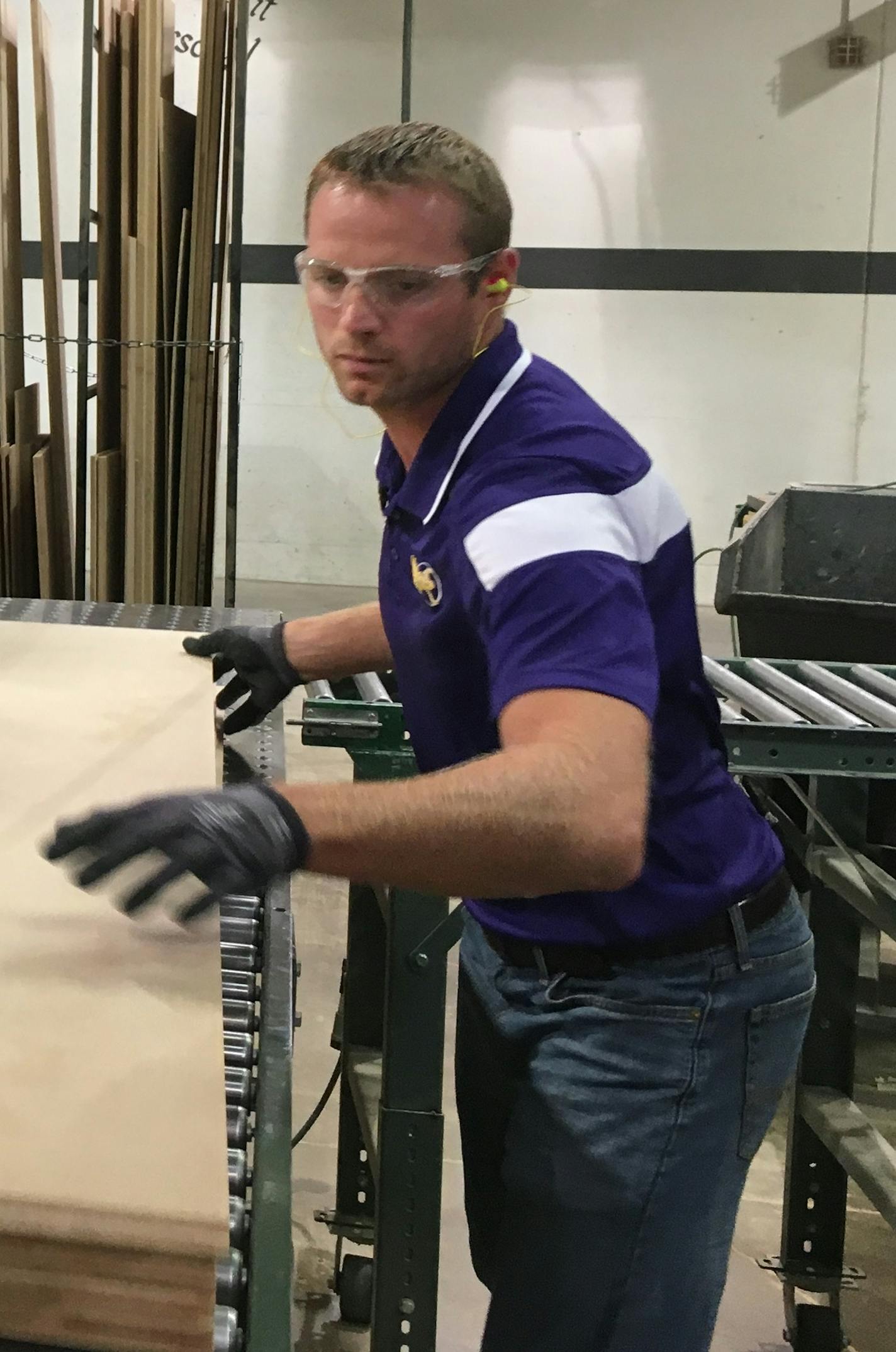 Waconia High School teacher Peter Brown grabs a wooden sheet. Brown is participating in a two-week training with ELKAY &#xf1; Medallion Cabinetry and Applied Vacuum Technology Inc.