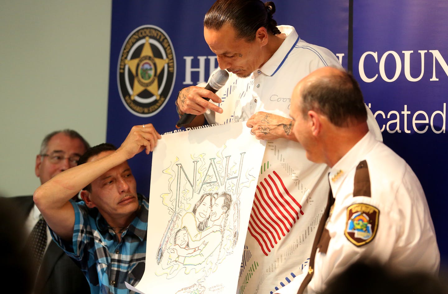 James Cross with his twin brother Gerald Cross held up a poster for a new organization Native Americans Against Heroin. ] (KYNDELL HARKNESS/STAR TRIBUNE) kyndell.harkness@startribune.com Heroin Town Hall at Church of Gichitwaa Kateri in Minneapolis Min., Thursday, May 28, 2015.