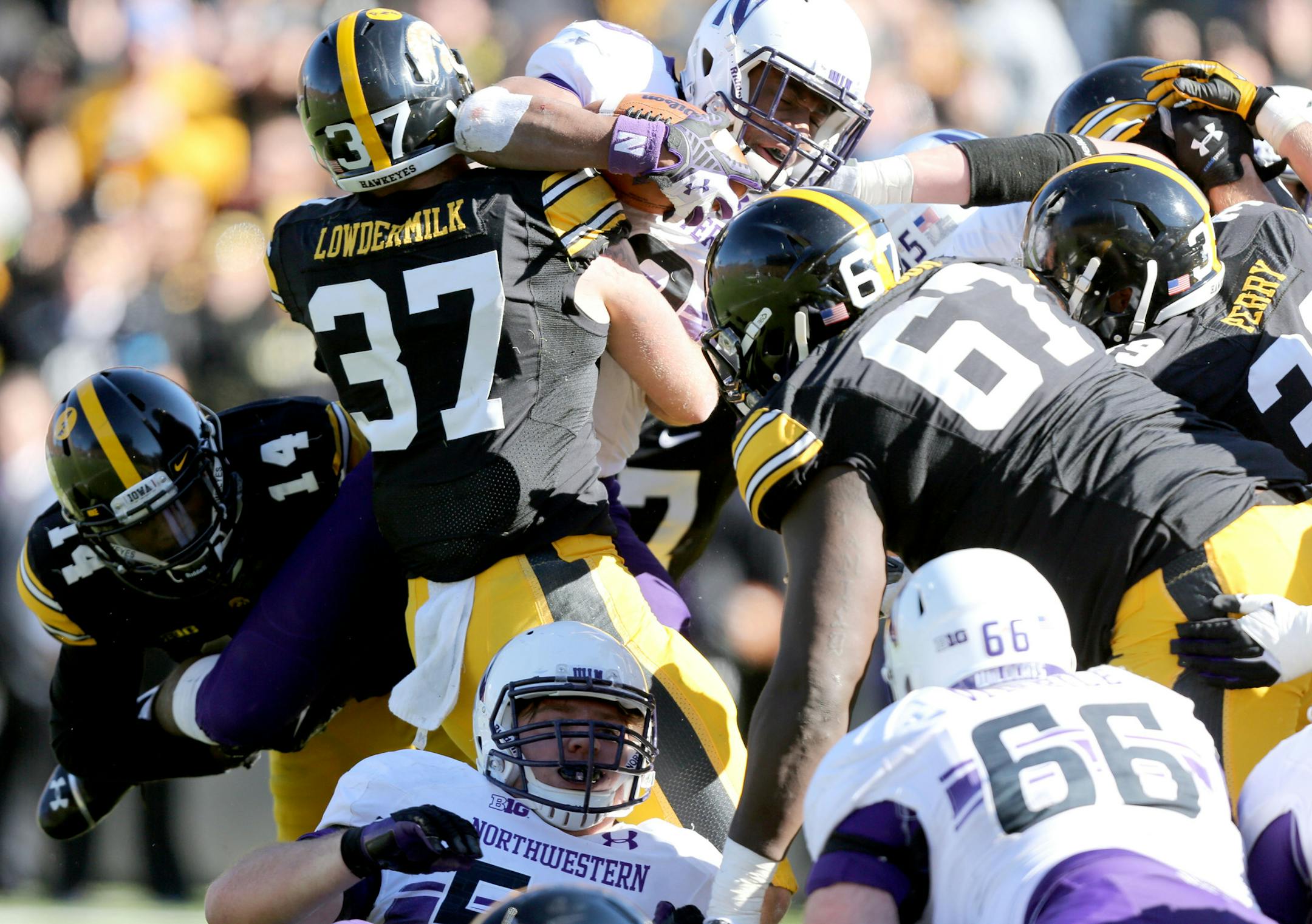 Iowa defensive backs Desmond King (14) and John Lowdermilk (37) and the rest of the Iowa defense stuff Northwestern running back Justin Jackson (28) as he tries to jump into the end zone on a fourth and goal play during the second half of an NCAA college football game, Saturday, Nov. 1, 2014, in Iowa City, Iowa. Iowa won 48-7. (AP Photo/Justin Hayworth)