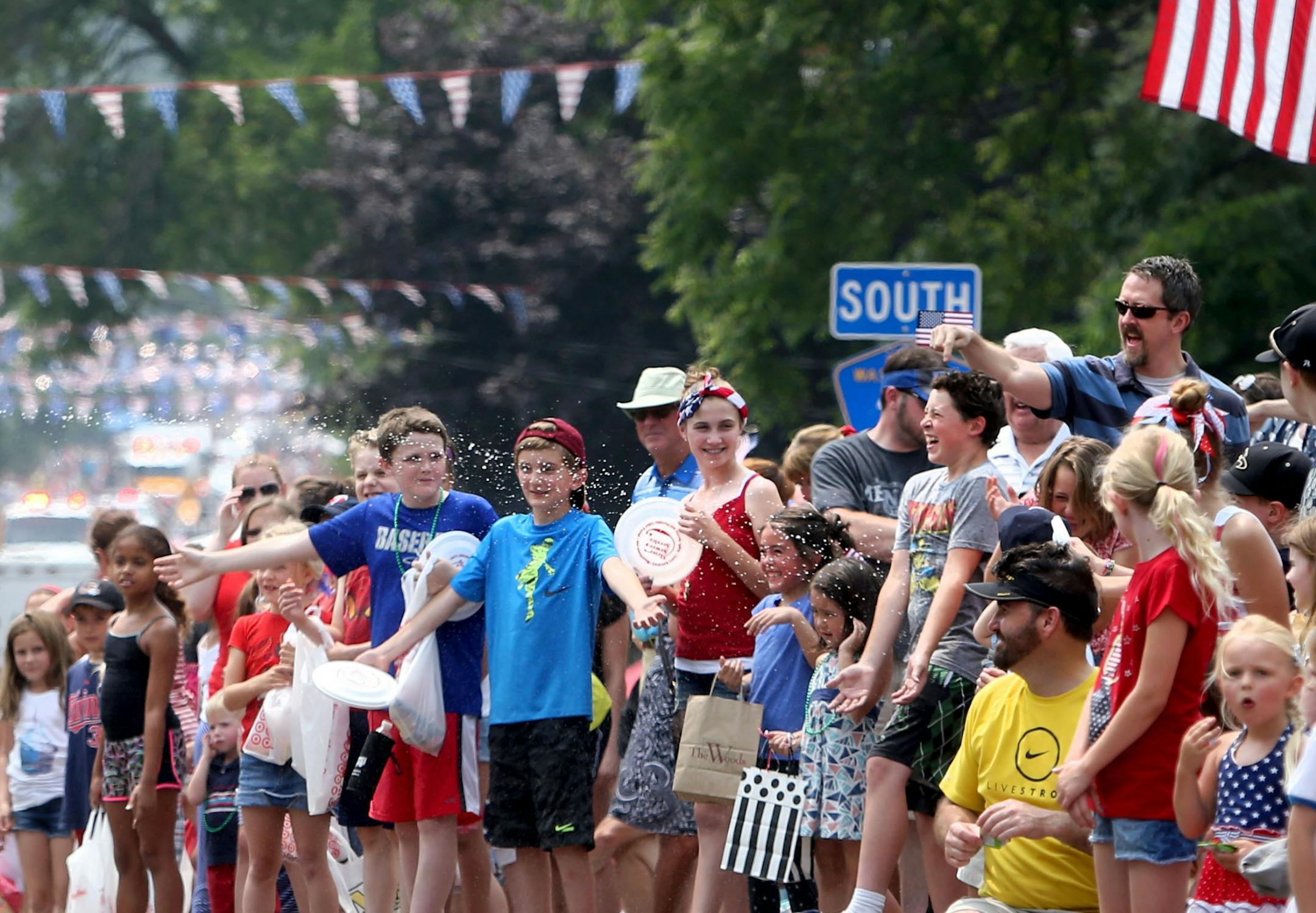Parade goers enjoyed a stream of water from a passing truck with squirt guns during the July 4th parade in downtown Afton, MN, Saturday, July 4, 2015.