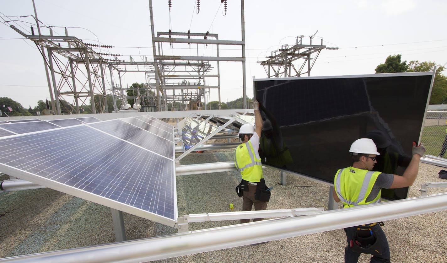 Foreman James Drummond, left, and installer Anthony Acosta of TruNorth Solar lift a solar panel in place at a Dakota Electric Association solar array constructed in Farmington, Minn., in August 2014. The project is one of more than 20 solar arrays being built by Minnesota electric coooperatives across the state.