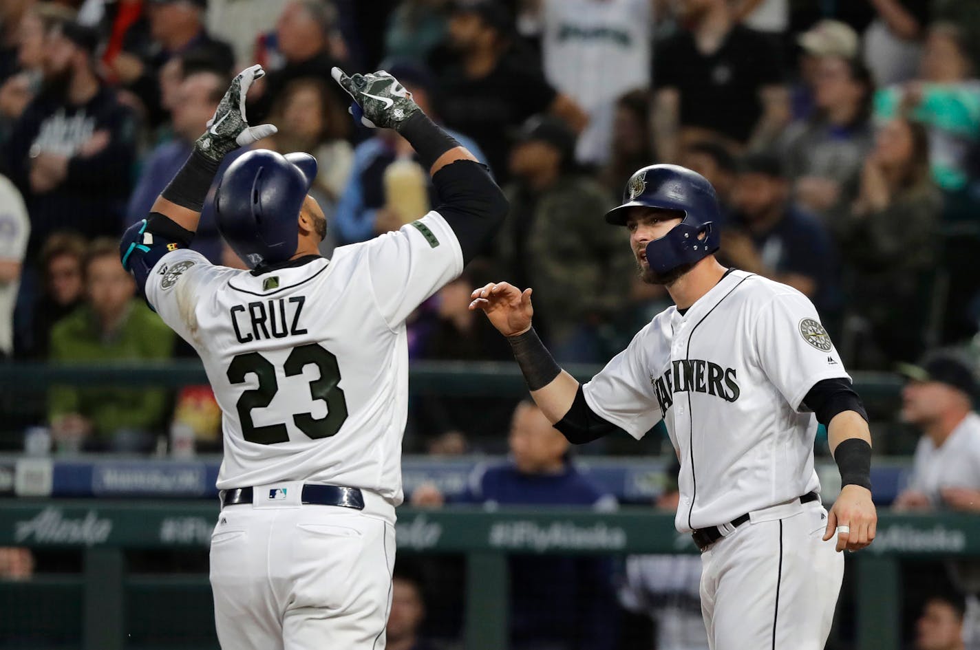 Nelson Cruz is greeted at the plate by Mitch Haniger, right, after Cruz hit a two-run home run to score Haniger during the sixth inning