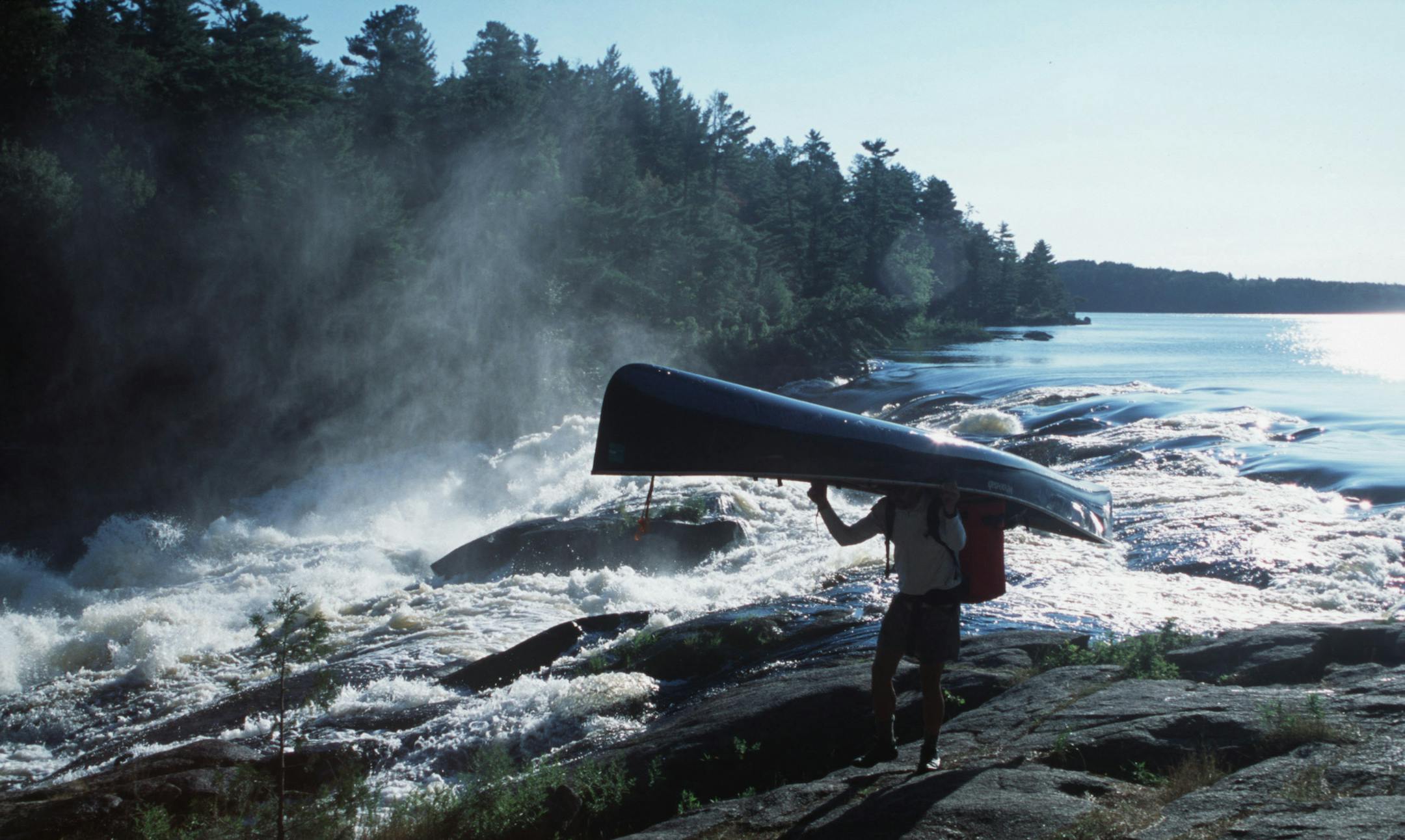 Steve Piragis of Ely MN portages his canoe around roaring Curtain Falls on Crooked Lake along the Minnesota-Ontario border during a late-summer boundary waters trek. This photo ran in color Sunday Sept 9, 2001, page C20. Photo by Star Tribune outdoors writer Doug Smith. ORG XMIT: MIN2013083013065214 ORG XMIT: MIN1308301308090068 ORG XMIT: MIN1405161416080157