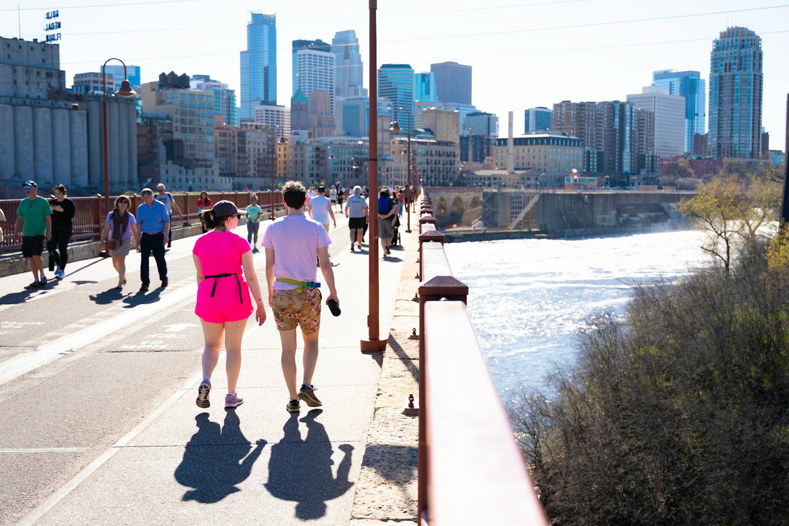 A couple walk across the Stone Arch Bridge with other pedestrians on the final day before the bridge is closed for construction on April 14, 2024, in Minneapolis.