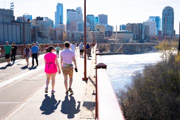 A couple walks across the Stone Arch Bridge with other pedestrians on the final day before the bridge is closed for construction on Sunday, April 14, 