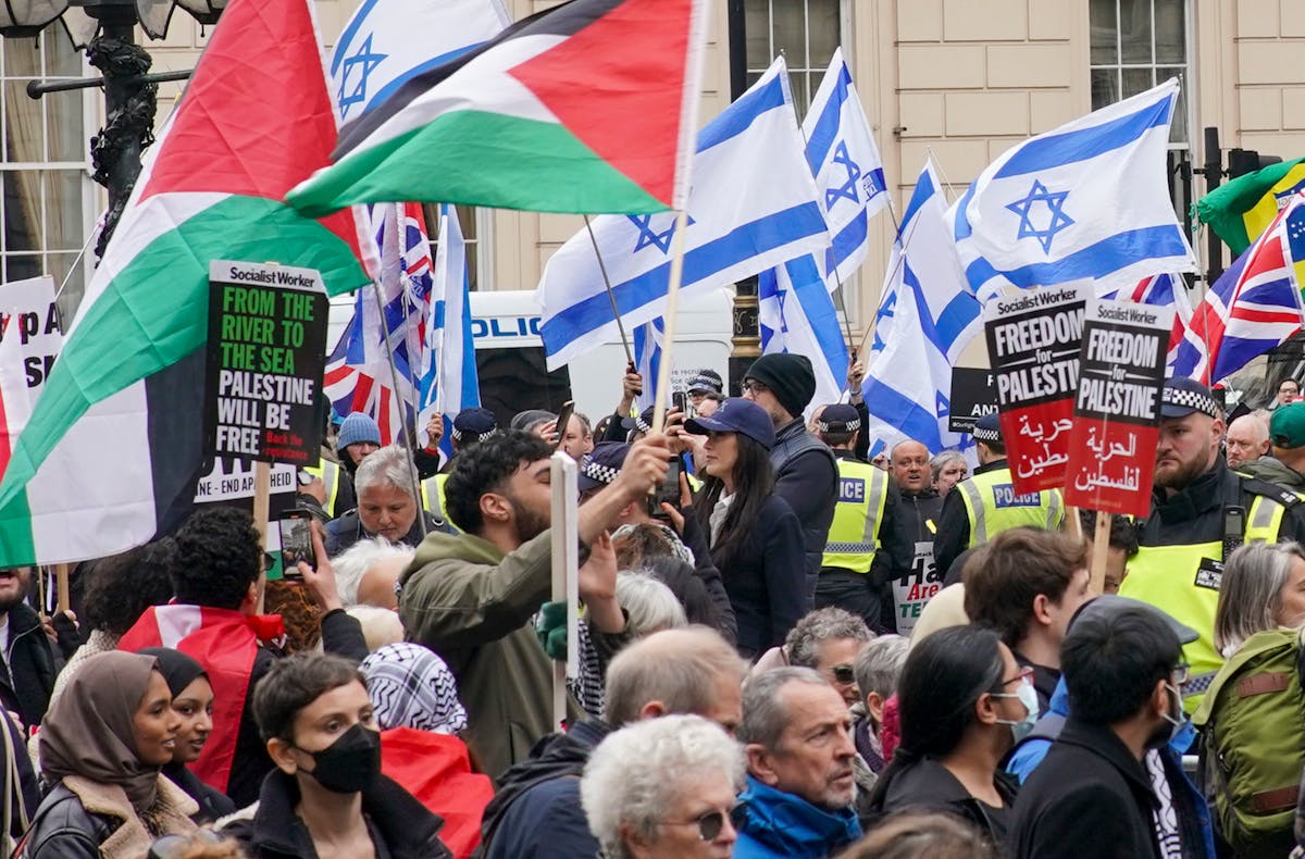 People take part in a pro-Palestine march as they walk past a counter protest with Israeli flags, at Waterloo Place in central London on April 27.