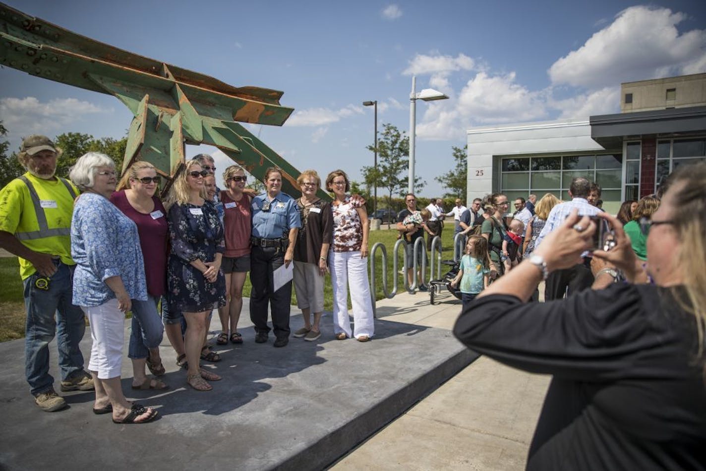 A group of survivors of the Interstate 35W bridge collapse posed for a picture with Lt. Kim Lund, who has worked with many survivors and families over the last ten years, at a dedication for a piece of the wreckage displayed at the Emergency Operations Center Tuesday, Aug. 1, 2017, in Minneapolis, as a reminder of the first responders' dedication and service on the day of the I-35W bridge collapse ten years ago.