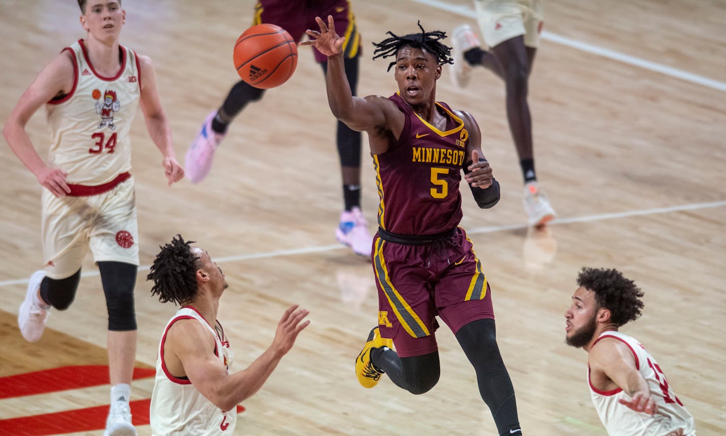 Marcus Carr leaps to pass the ball to the wing as Nebraska guard Trey McGowens, lower left, Kobe Webster, right, and Thorir Thorbjarnarson (34) watch during the first half