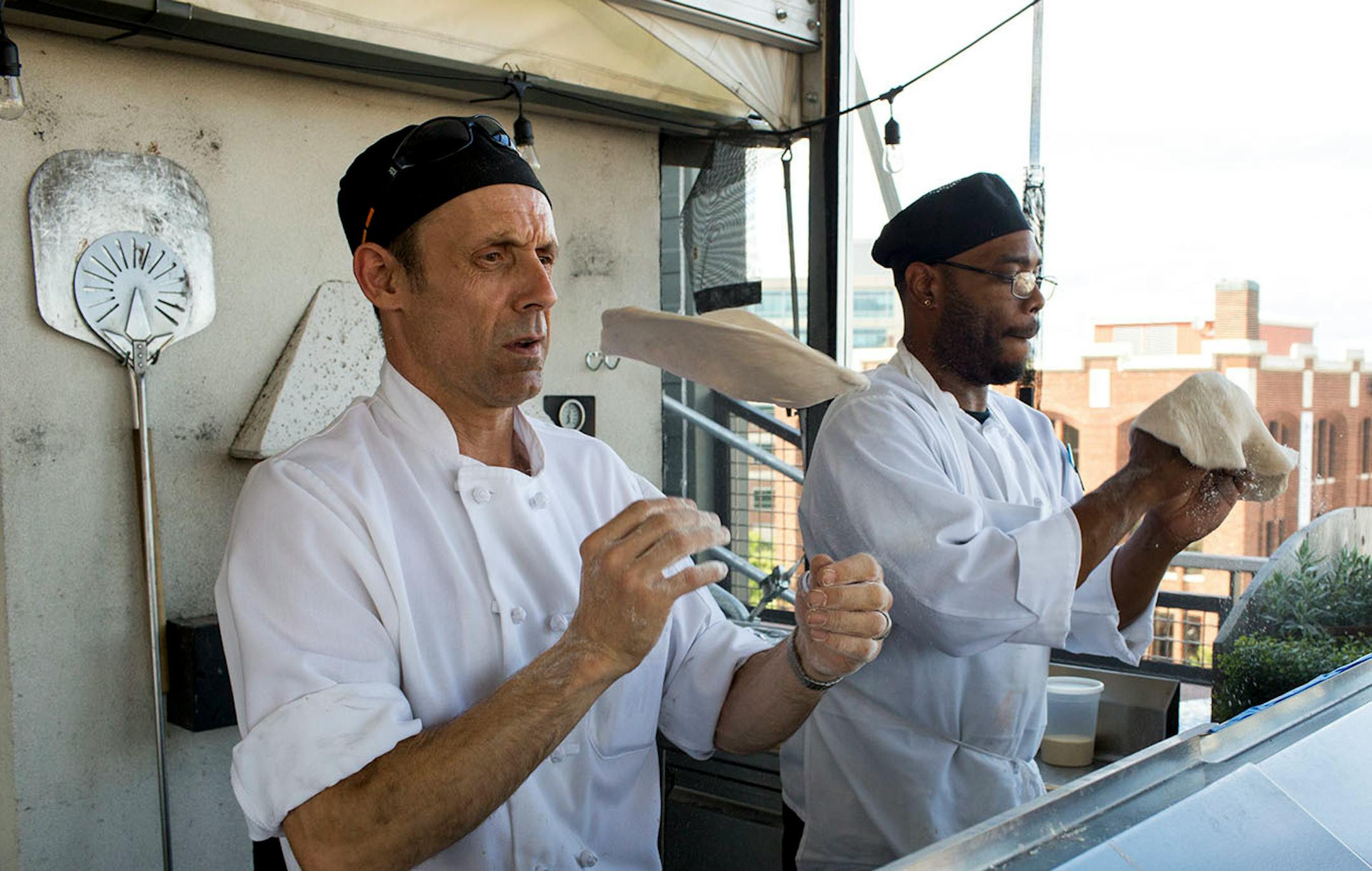 Jim Crisp (left) and Ronnie Walker stretch pizza dough for the open-air rooftop patio dining. ] COURTNEY PEDROZA • courtney.pedroza@startribune.com June 22-24, 2017; Wisconsin restaurants, cafes, bars, bakeries and breweries; Dining along the Mississippi River.