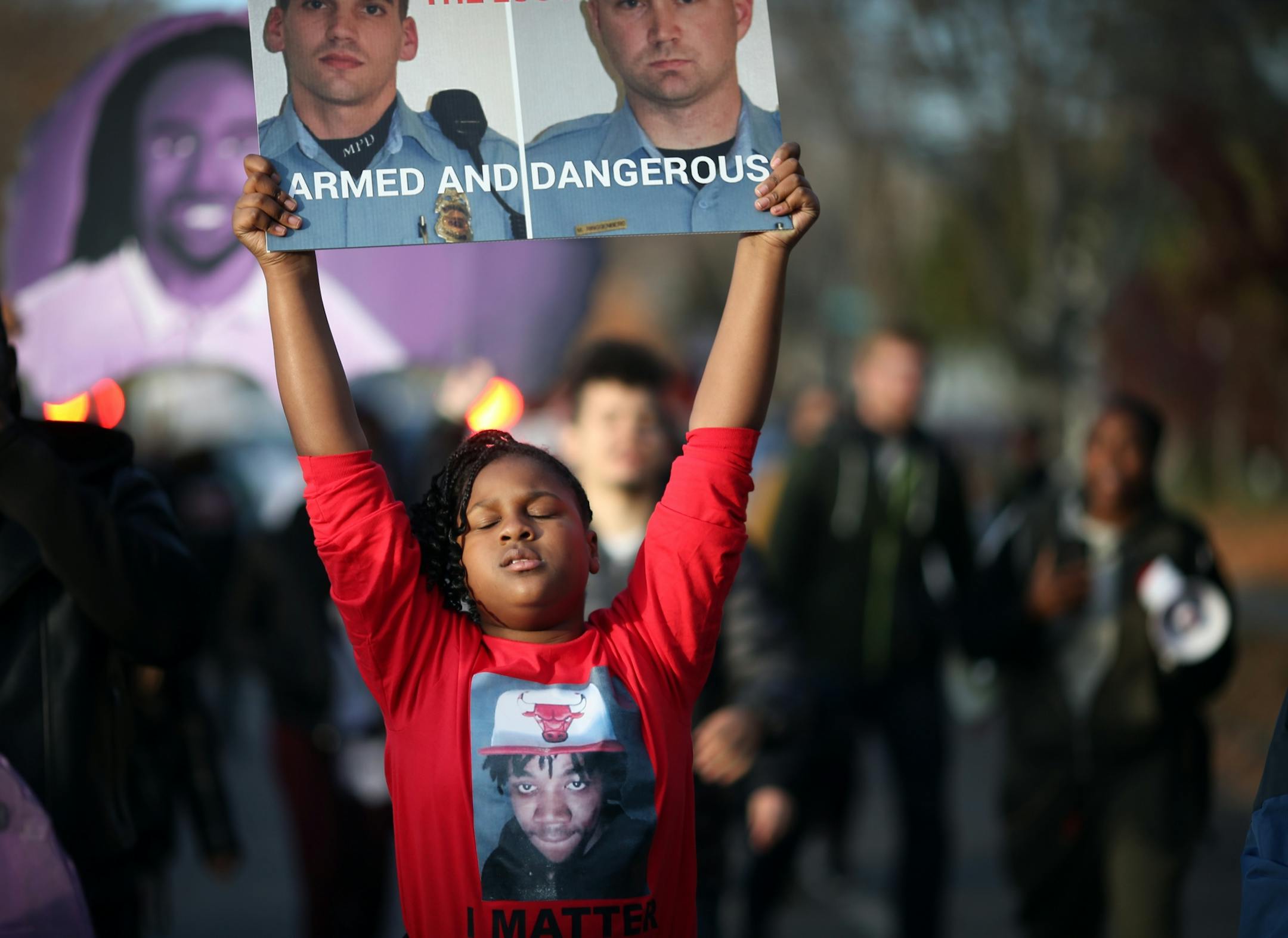 A niece of Jamar Clark protested with a photograph of the two Minneapolis Police that were involved in Clark�s death. Family members, friends and activists marched too the spot where Jamar Clark was killed in a confrontation with city police last fall to commemorate his death Tuesday October 15, 2016 in Minneapolis, MN.