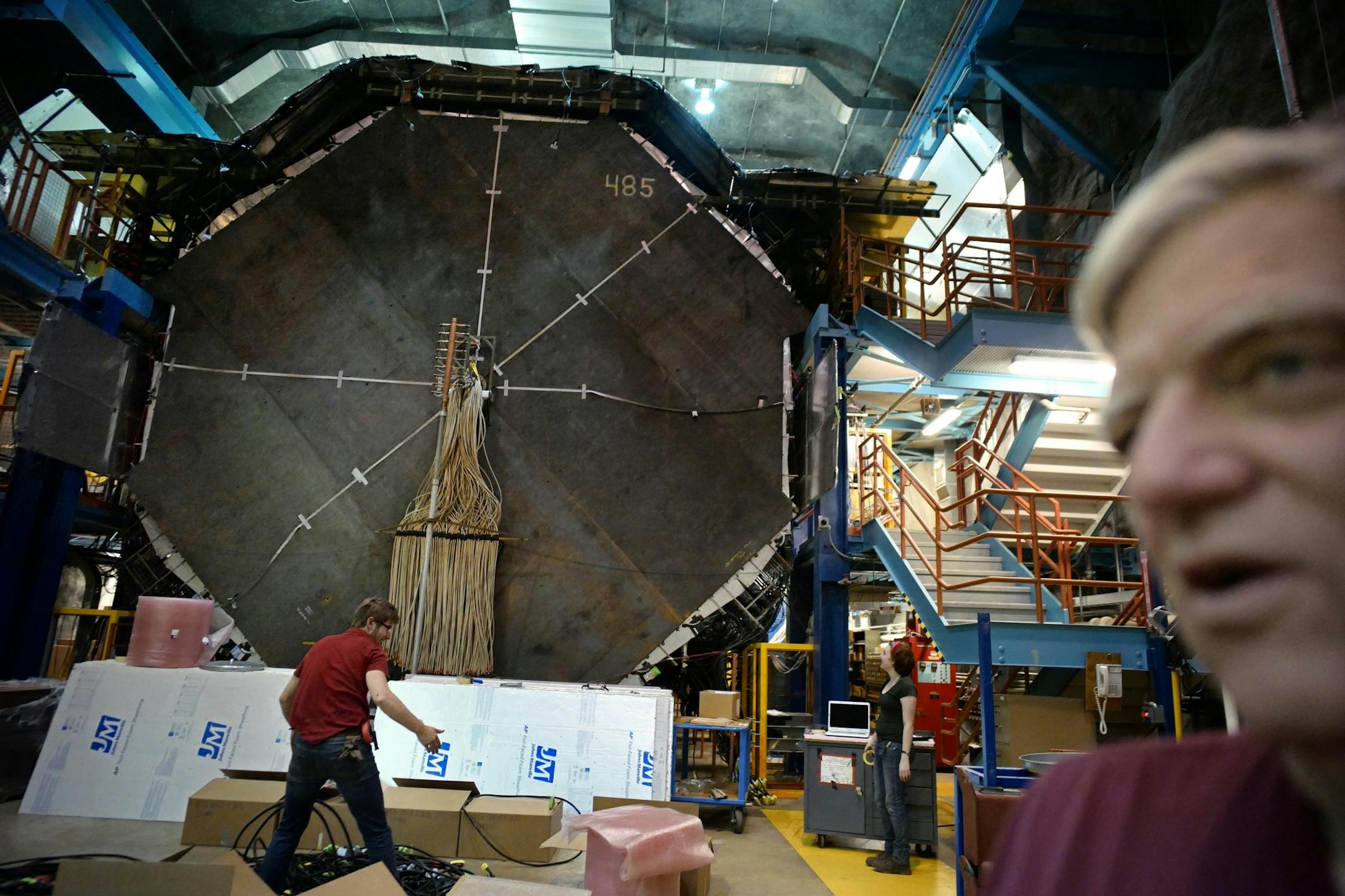 In the back ground of Soudan Underground Laboratory manager Meier are the 6000 tons of steel plates which are used like stop signs for neutrinos. Supersensitive sensors between the steel plates collect evidence of neutrinos .