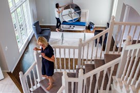 Showhomes franchise owner Karen Galler stands on the stairs while Sondra Bambery waits to place the mirror above the fireplace inside the Eden Prairie