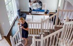 Showhomes franchise owner Karen Galler stands on the stairs while Sondra Bambery waits to place the mirror above the fireplace inside the Eden Prairie
