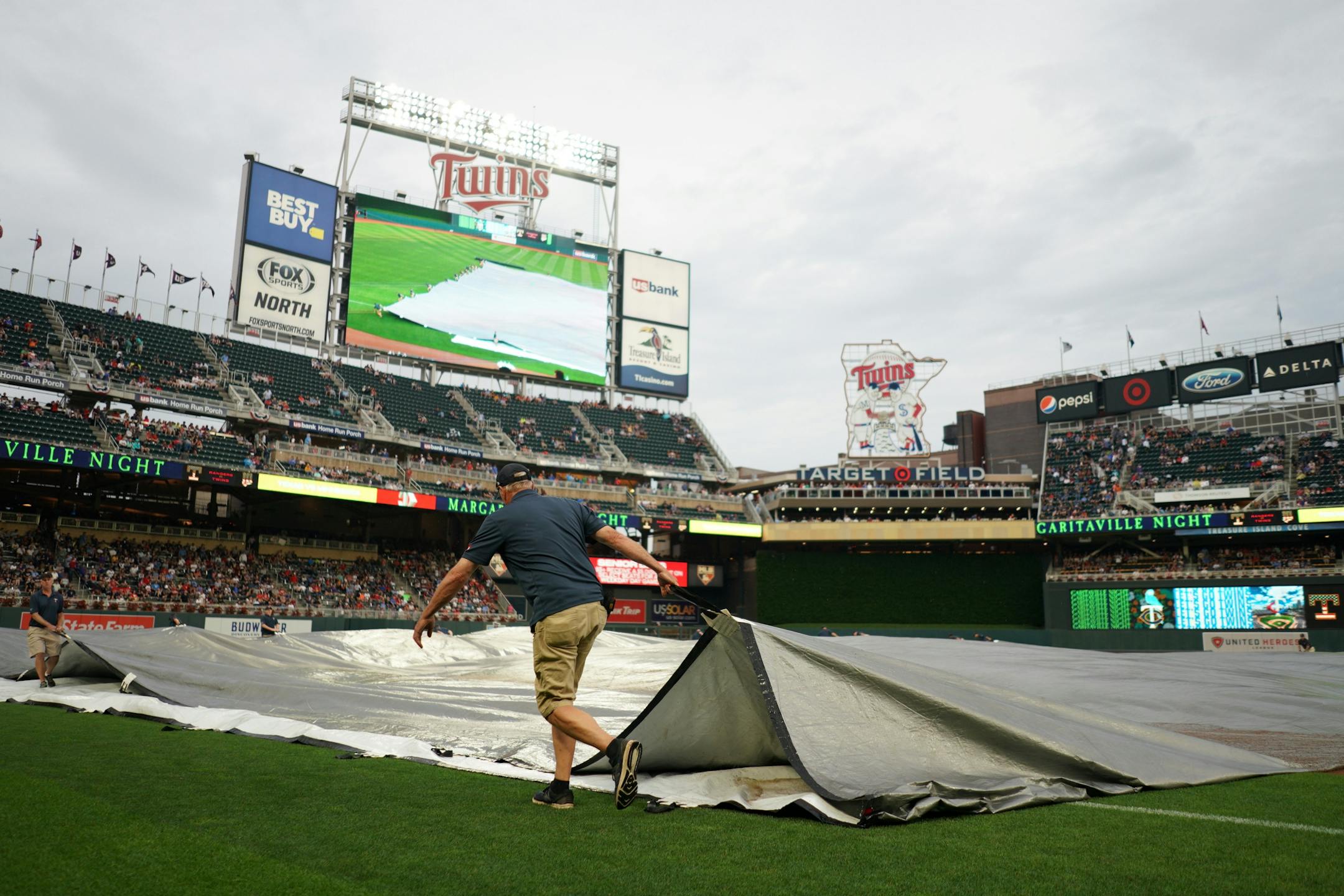 Members of the grounds crew removed the tarp from the infield following rain delay Friday at Target Field.
