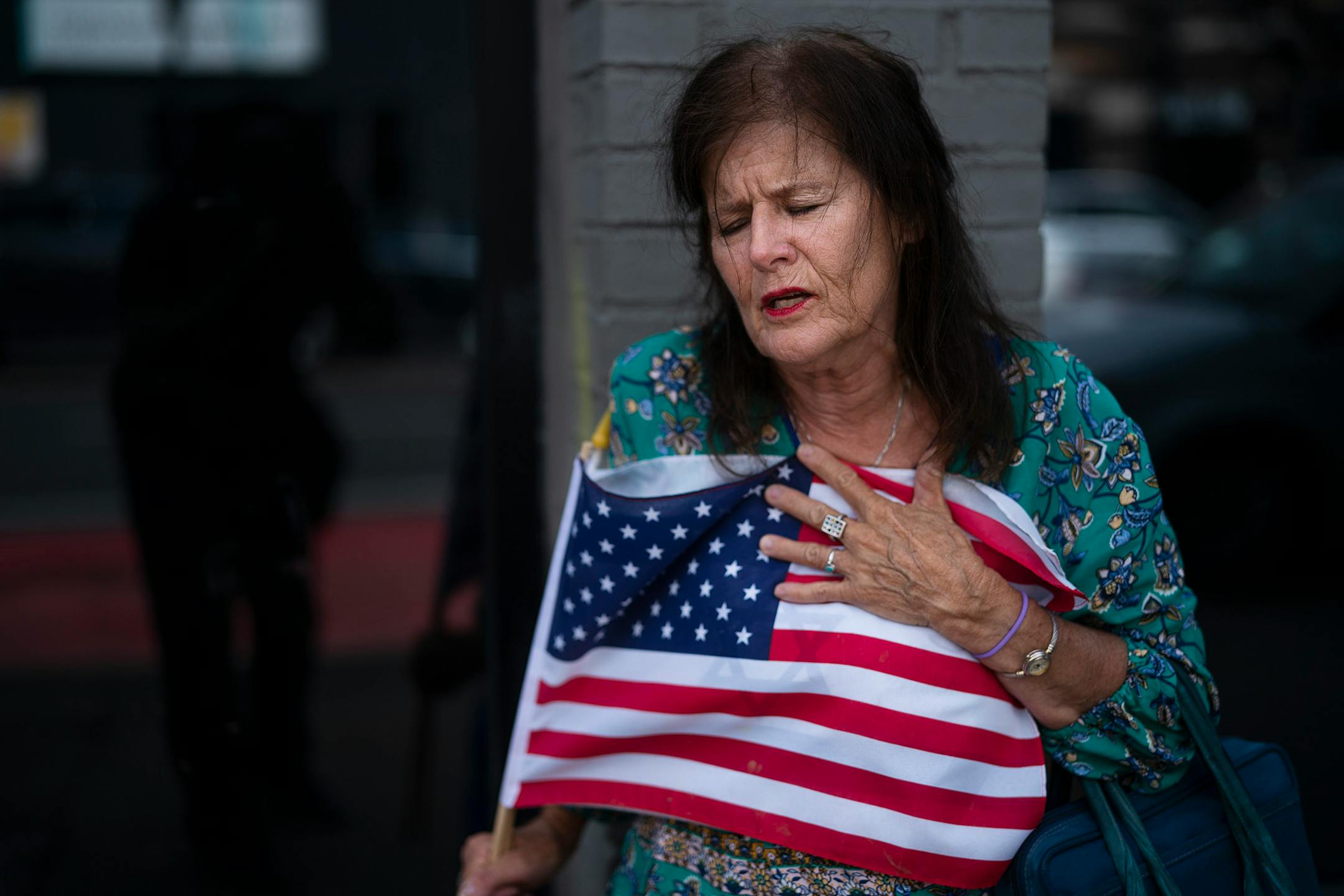 Merrilyn Downs clinched the U.S. flag as she prayed at the site where a shooting happened early Sunday morning in the 2900 block of Hennepin Avenue South.