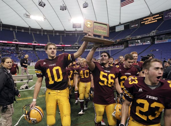 Mahnomen's Jacob Pavek (10) and Nick Otto (56) hold their team's trophy and celebrate their 20-14 1A Prep Bowl championship over Bethlehem Academy at 