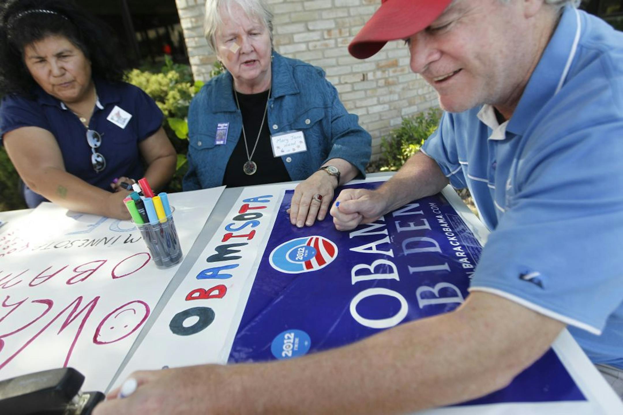 On Sunday at DFL headquarters in St. Paul, Rosa Reyes, Mary Jane Hand and Stephen Winkels worked on signs for the president, who is returning to the state Tuesday, barely two weeks since his last visit.